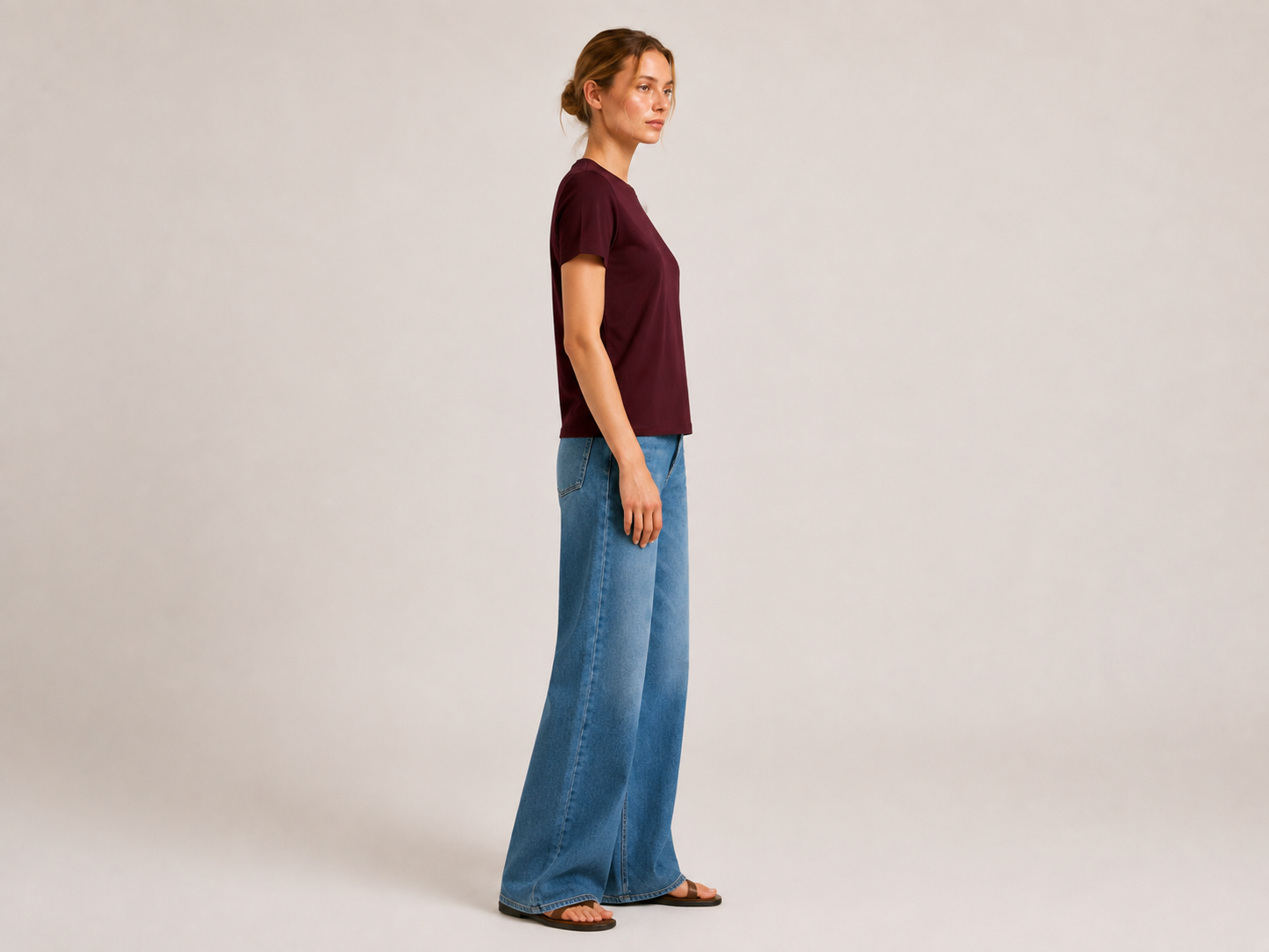 Side view of The Flax Studio chocolate mercerised cotton T-shirt worn with wide-leg jeans.