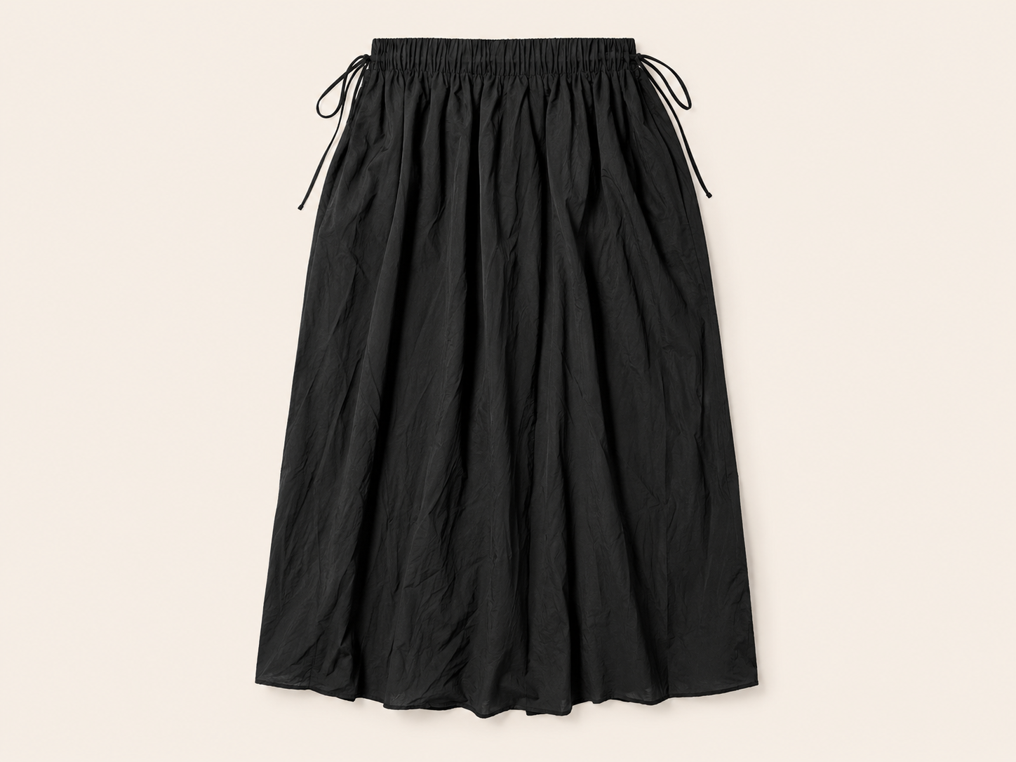 Flat lay of The Flax Studio black Cotton Tie Skirt, showing its gathered waistband and side ties.