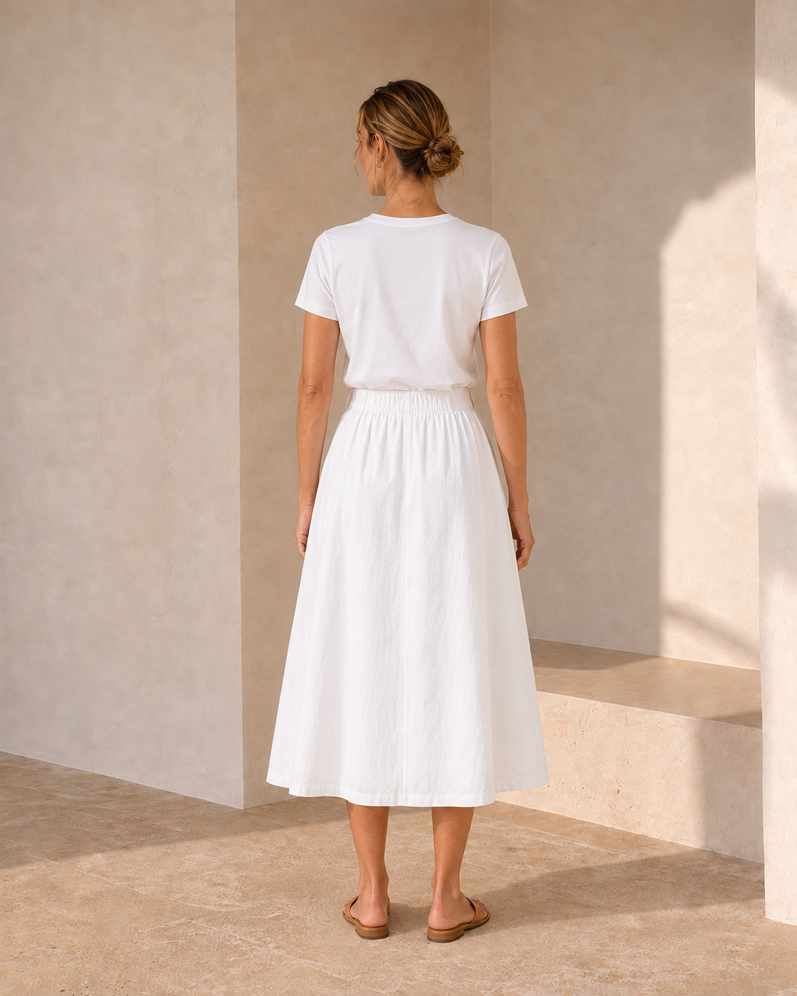 Back view of The Flax Studio white Button Front Skirt, showing its gathered waist and full midi silhouette.