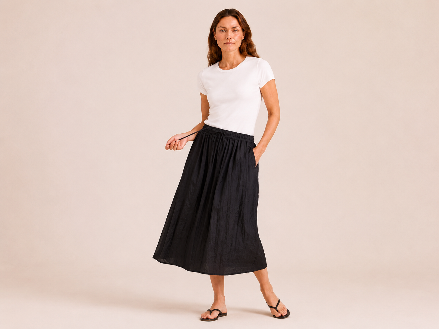 The Flax Studio black Cotton Tie Skirt styled with a white T-shirt, showing its gathered midi silhouette.