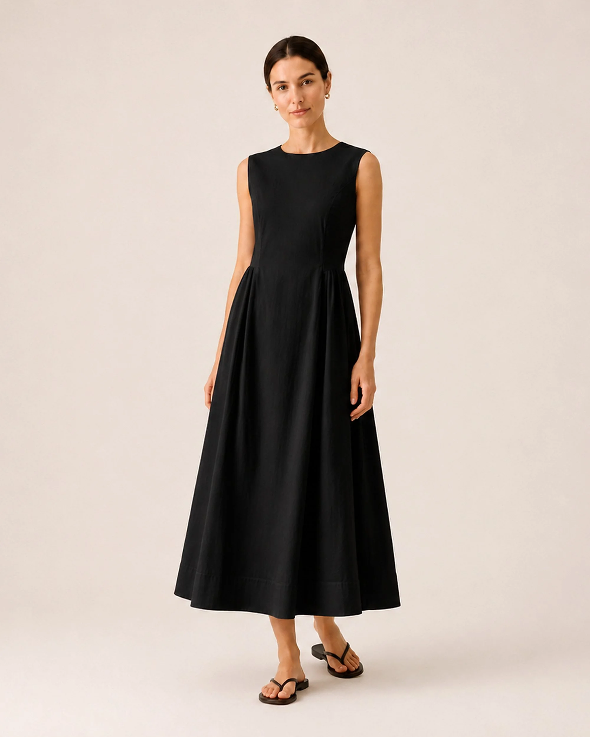 The Flax Studio black Tailored Dress, showing its sleeveless bodice, defined waist and A-line skirt.