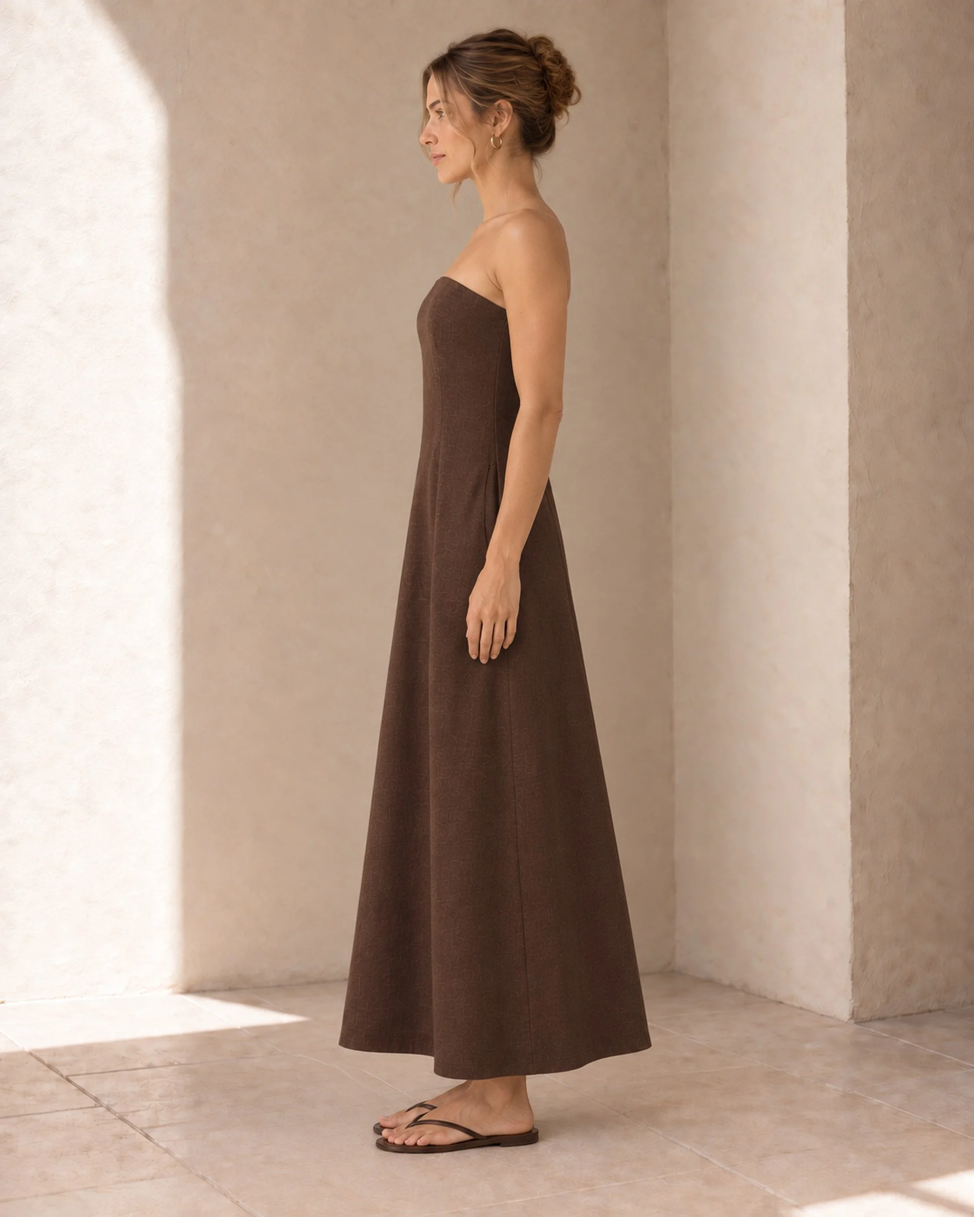 Side view of the Chocolate Strapless Linen Dress, showing its strapless bodice and flowing maxi skirt.