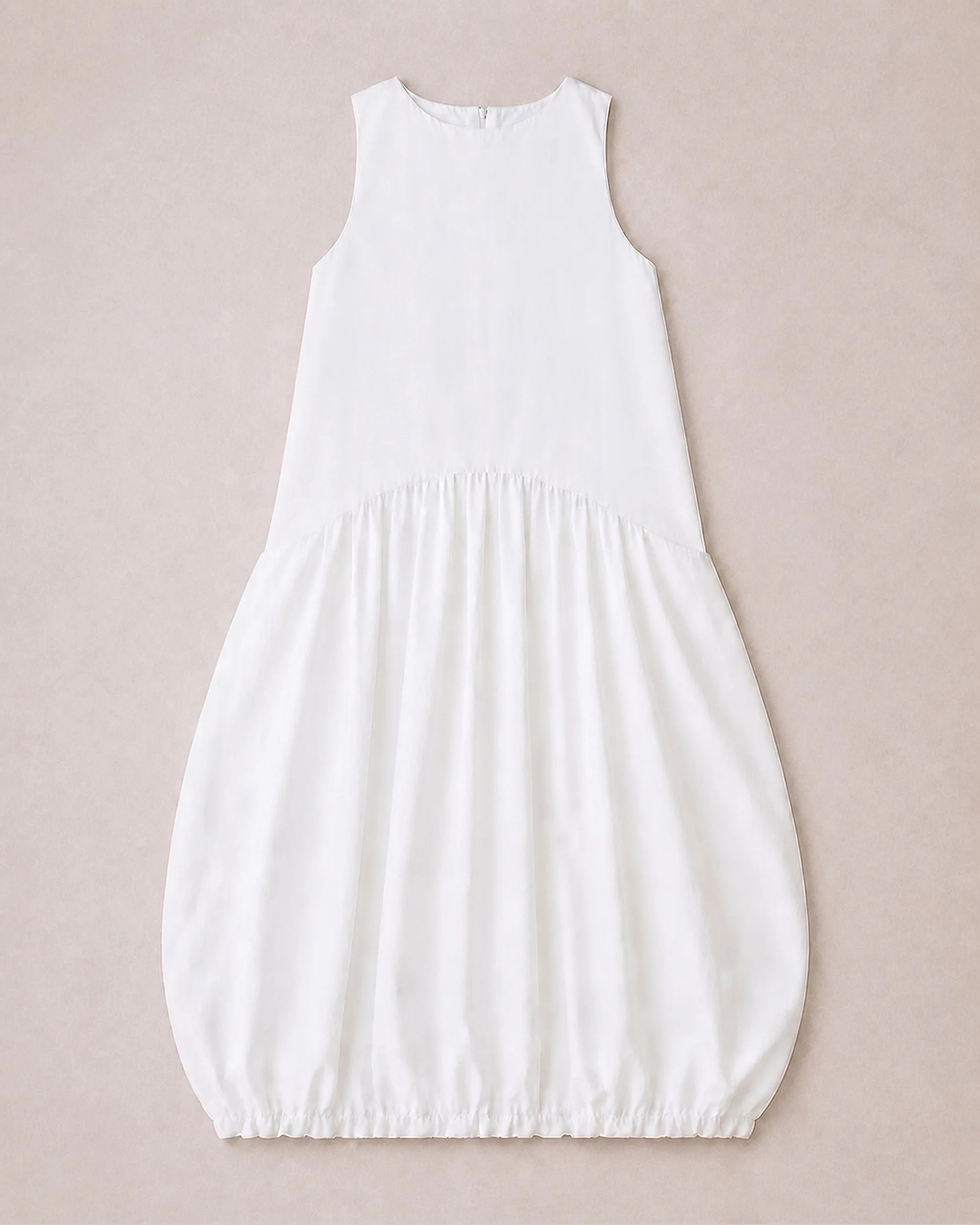 Flat lay of The Flax Studio white Arc Dress, showing the curved dropped seam and gathered skirt.