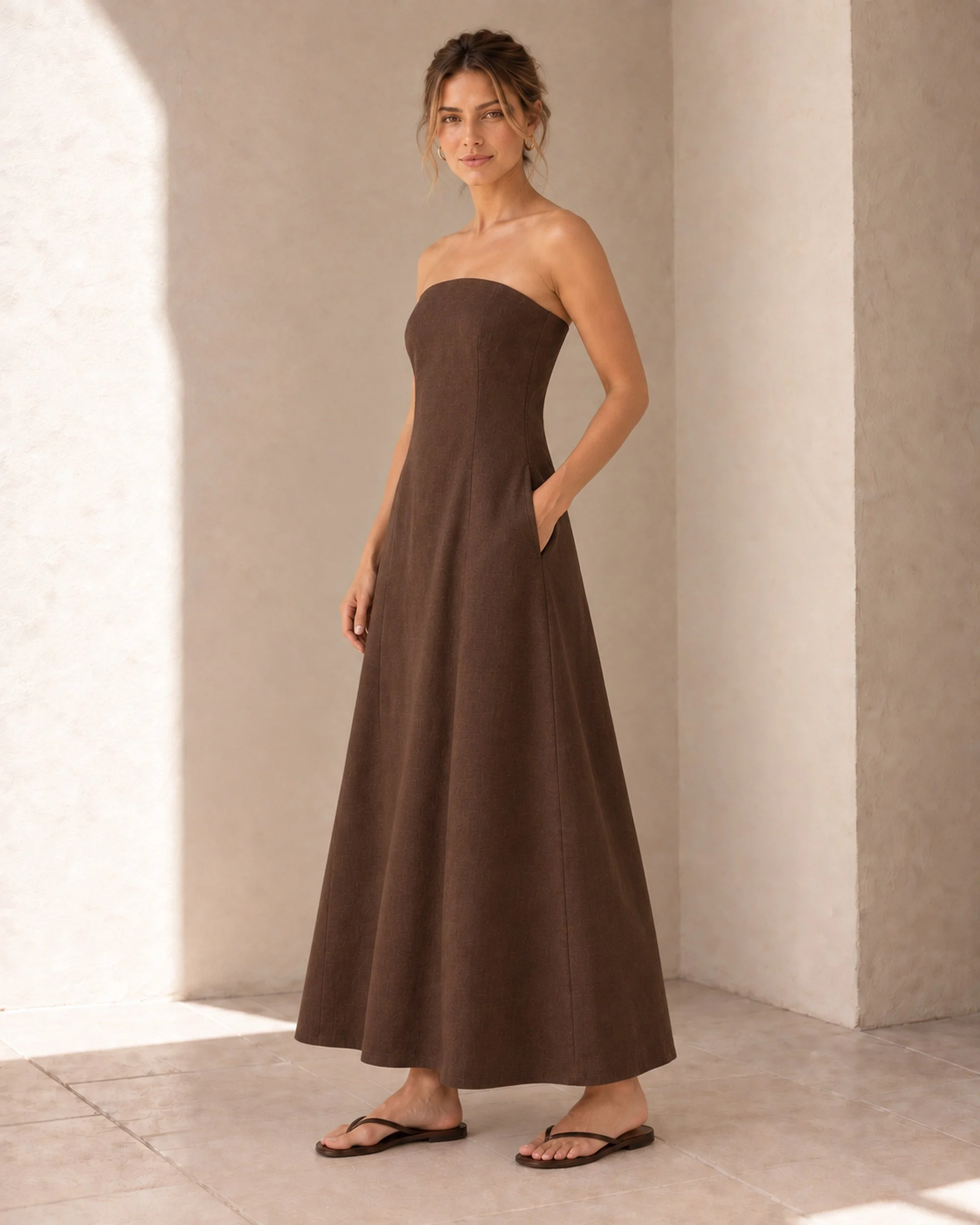 Three-quarter view of The Flax Studio Chocolate Strapless Linen Dress, showing the A-line shape and natural fabric drape.