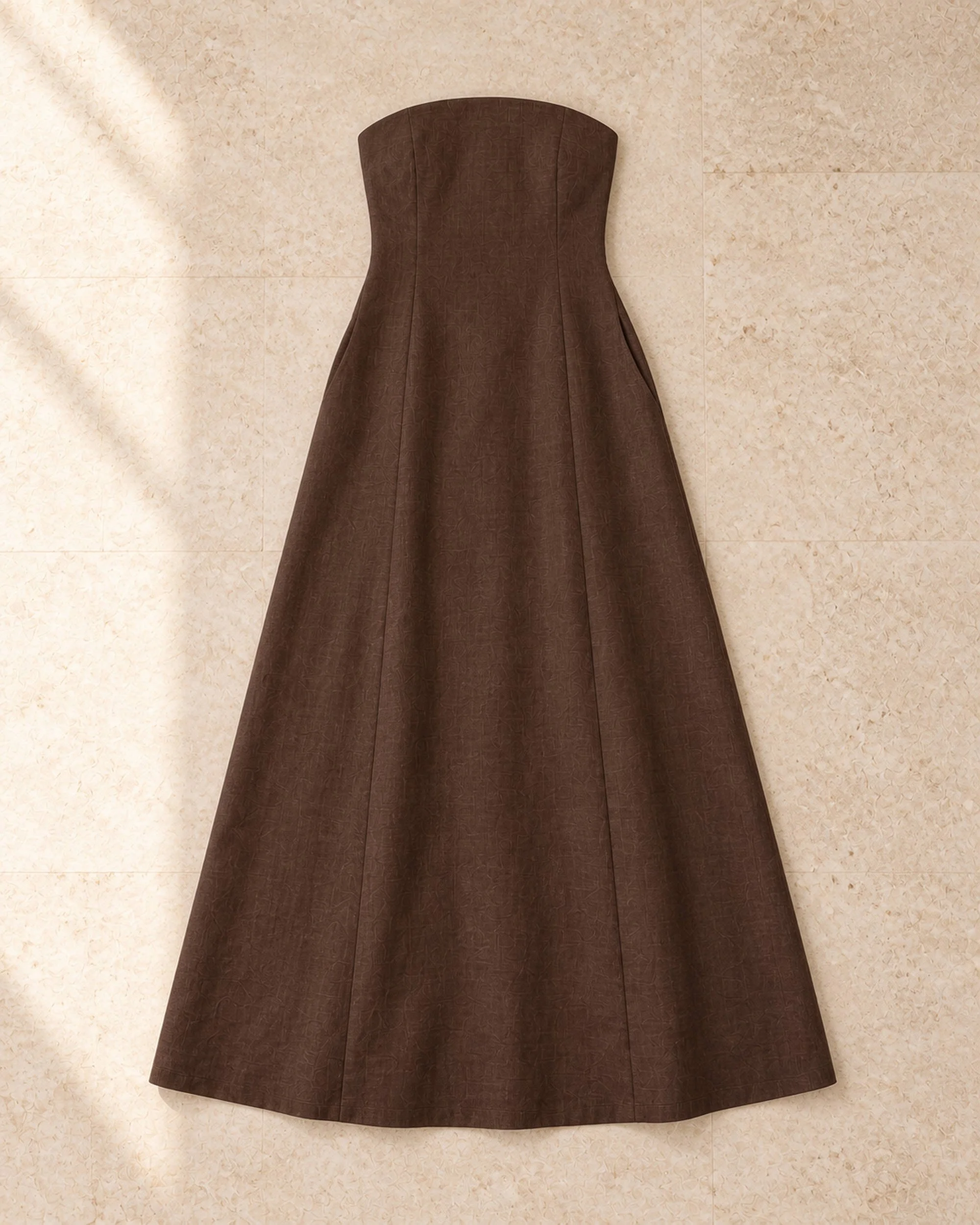 Flat lay of The Flax Studio Chocolate Strapless Linen Dress, showing the rounded neckline and A-line maxi shape.