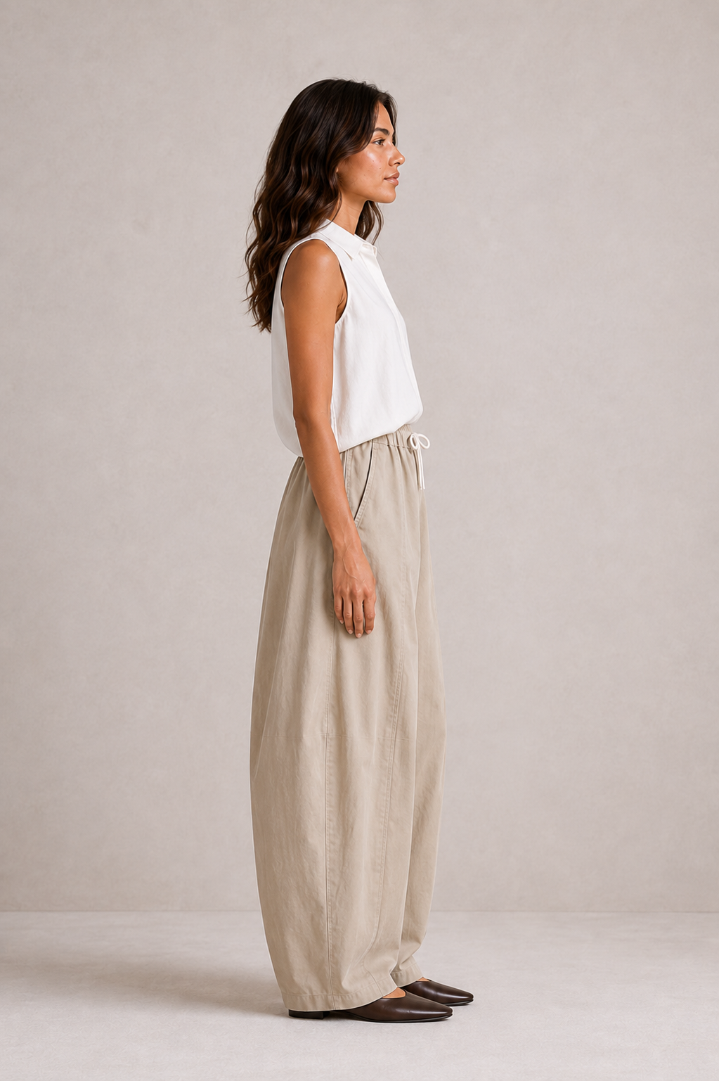 Side view of The Flax Studio tan Esme Pant, showing the curved leg and tapered hem.