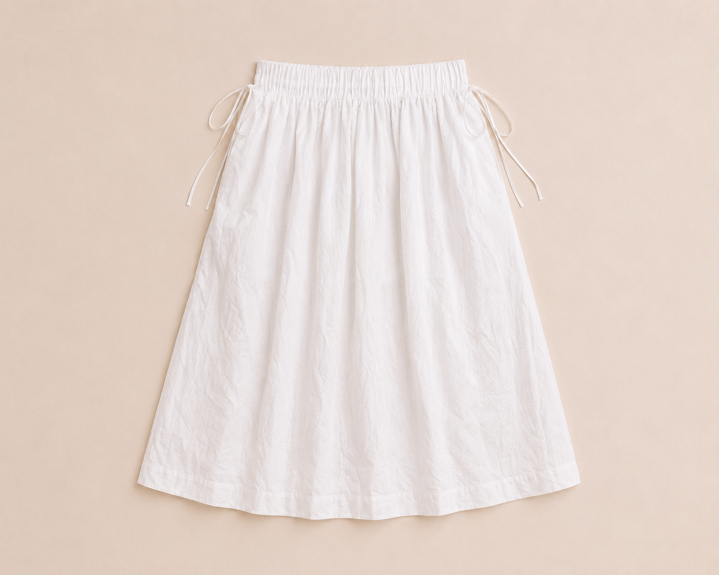 Flat lay of The Flax Studio white Cotton Tie Skirt with a gathered waistband and side ties.