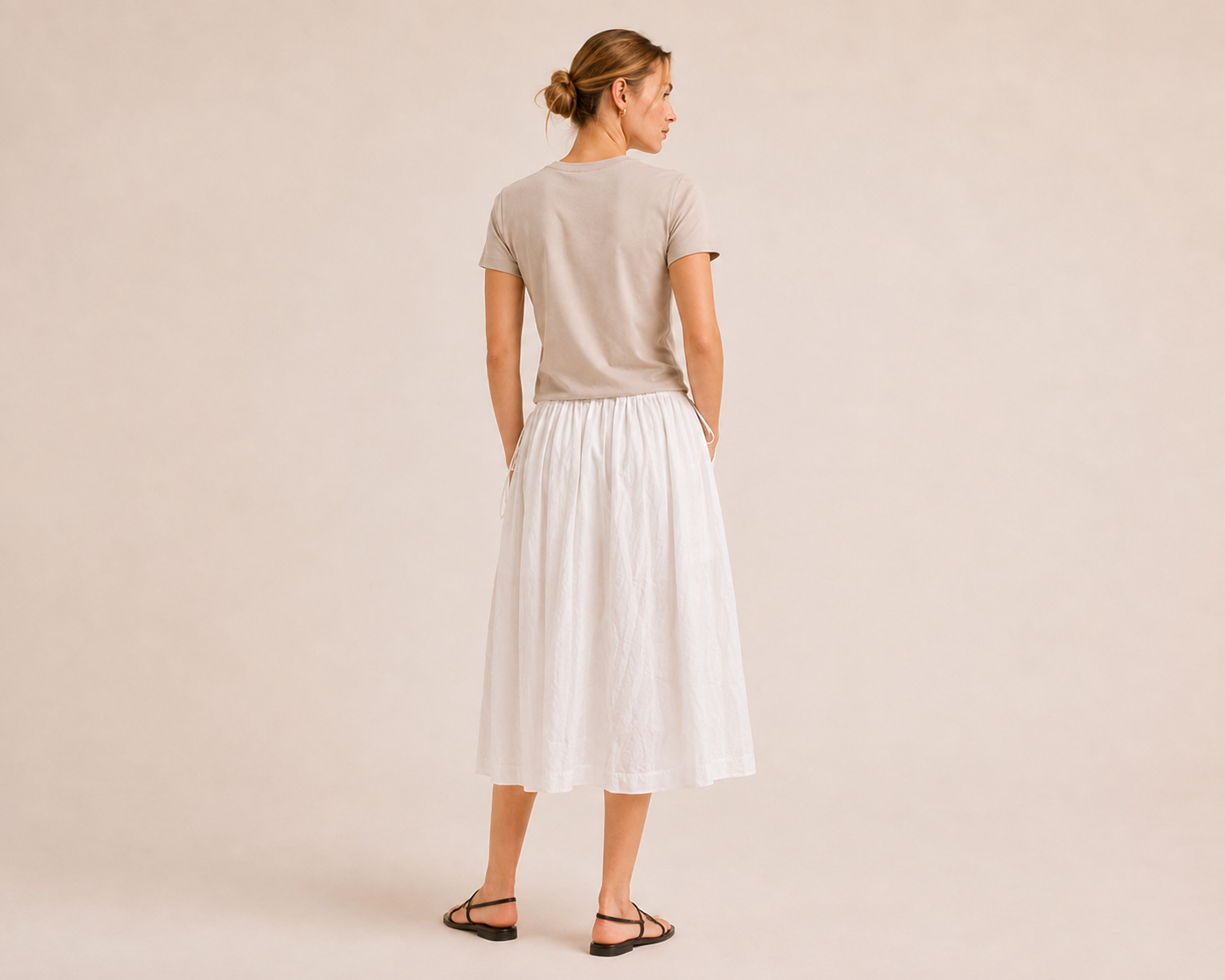 Back view of The Flax Studio white Cotton Tie Skirt worn with a sand T-shirt.