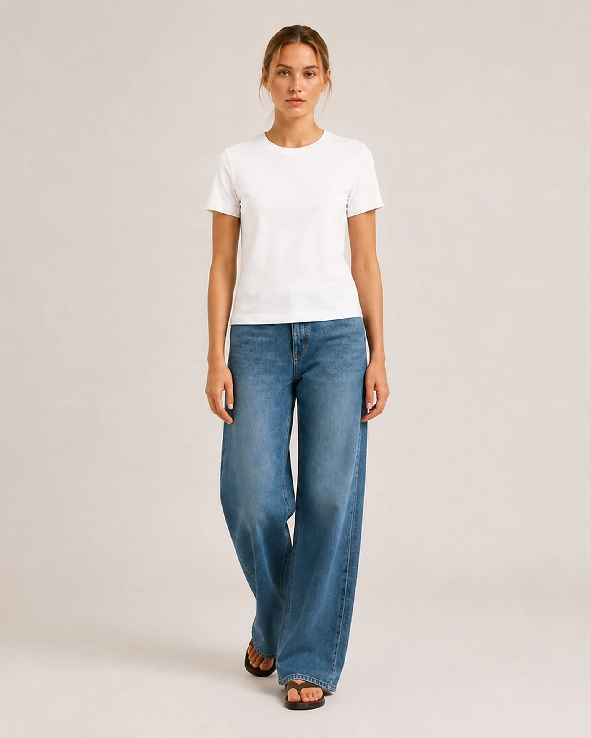 Front view of The Flax Studio white mercerised cotton T-shirt worn with blue jeans in a walking pose.