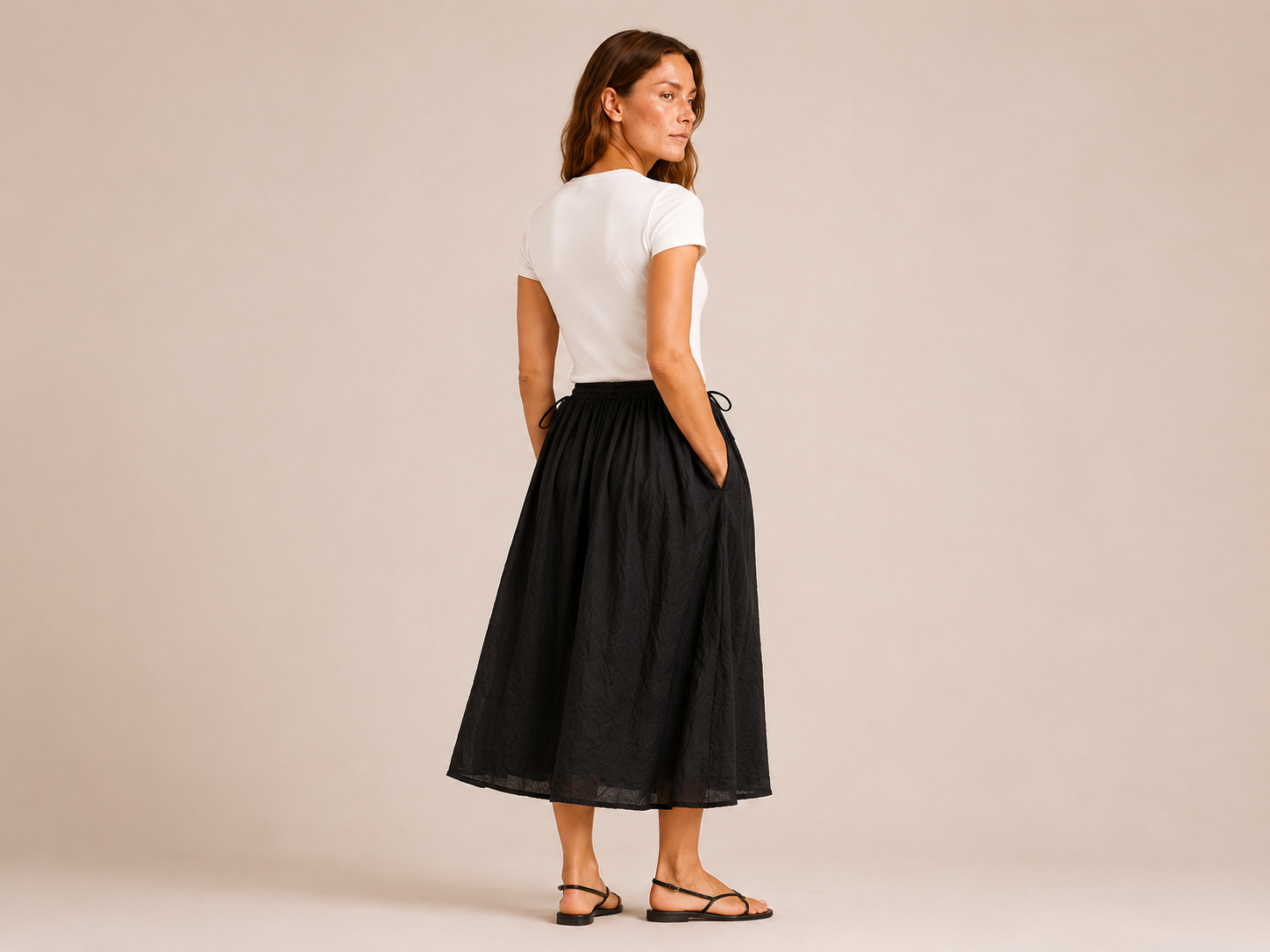 Angled back view of The Flax Studio black Cotton Tie Skirt, showing the relaxed midi shape.