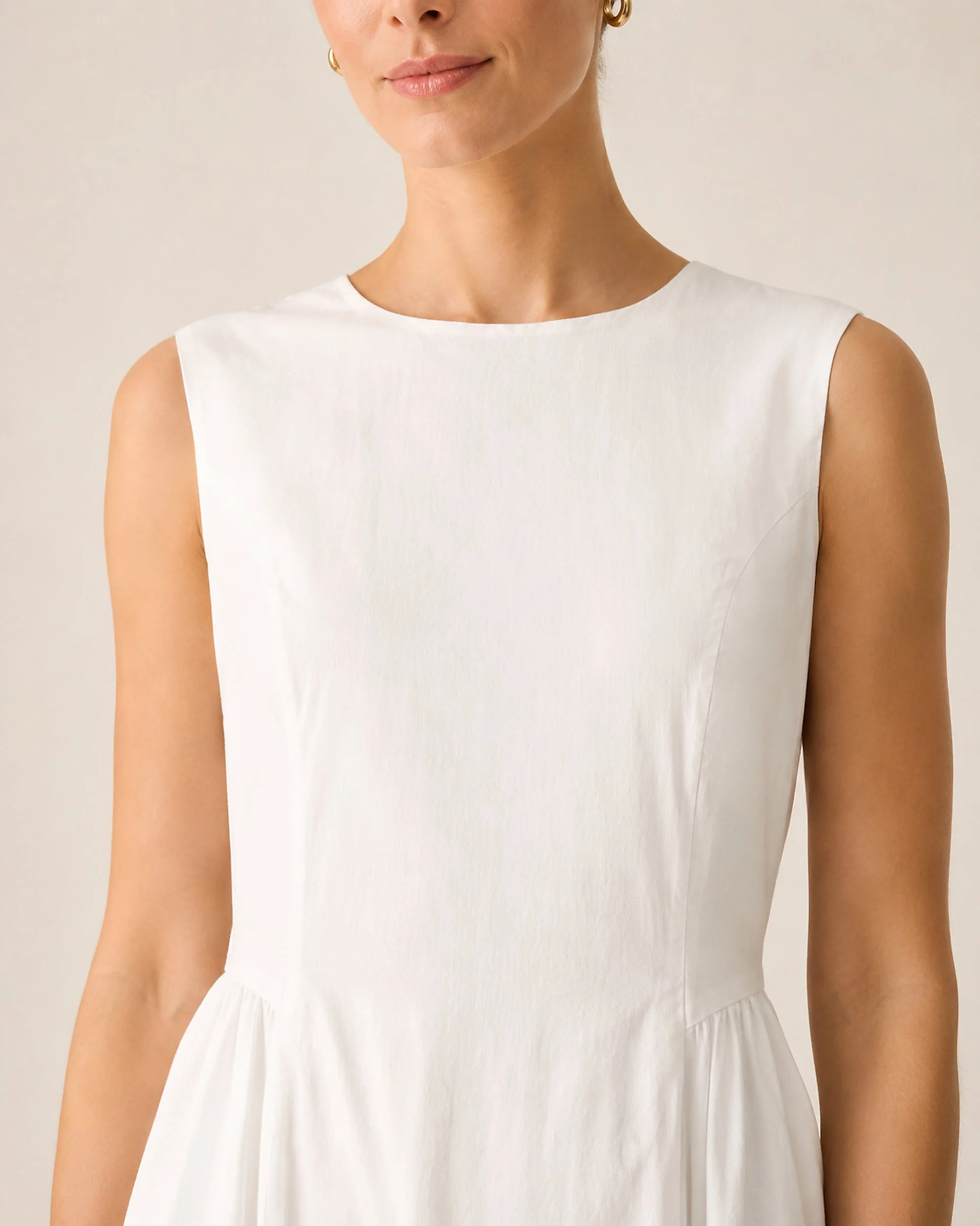 Close-up of The Flax Studio white Tailored Dress, showing the round neckline and sleeveless bodice.
