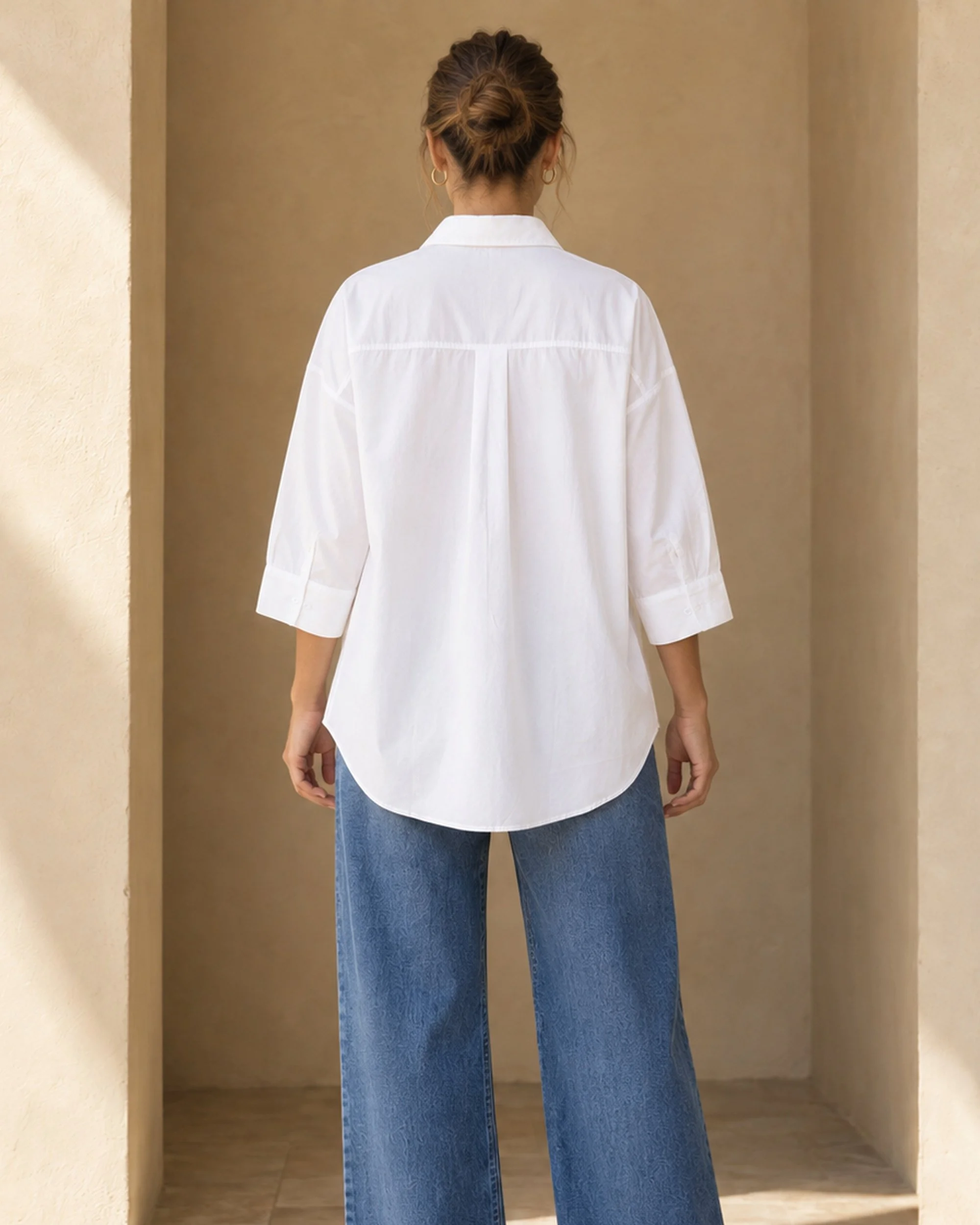 Back view of the white Oversized Cotton Shirt, showing its back yoke, centre pleat and curved hem.