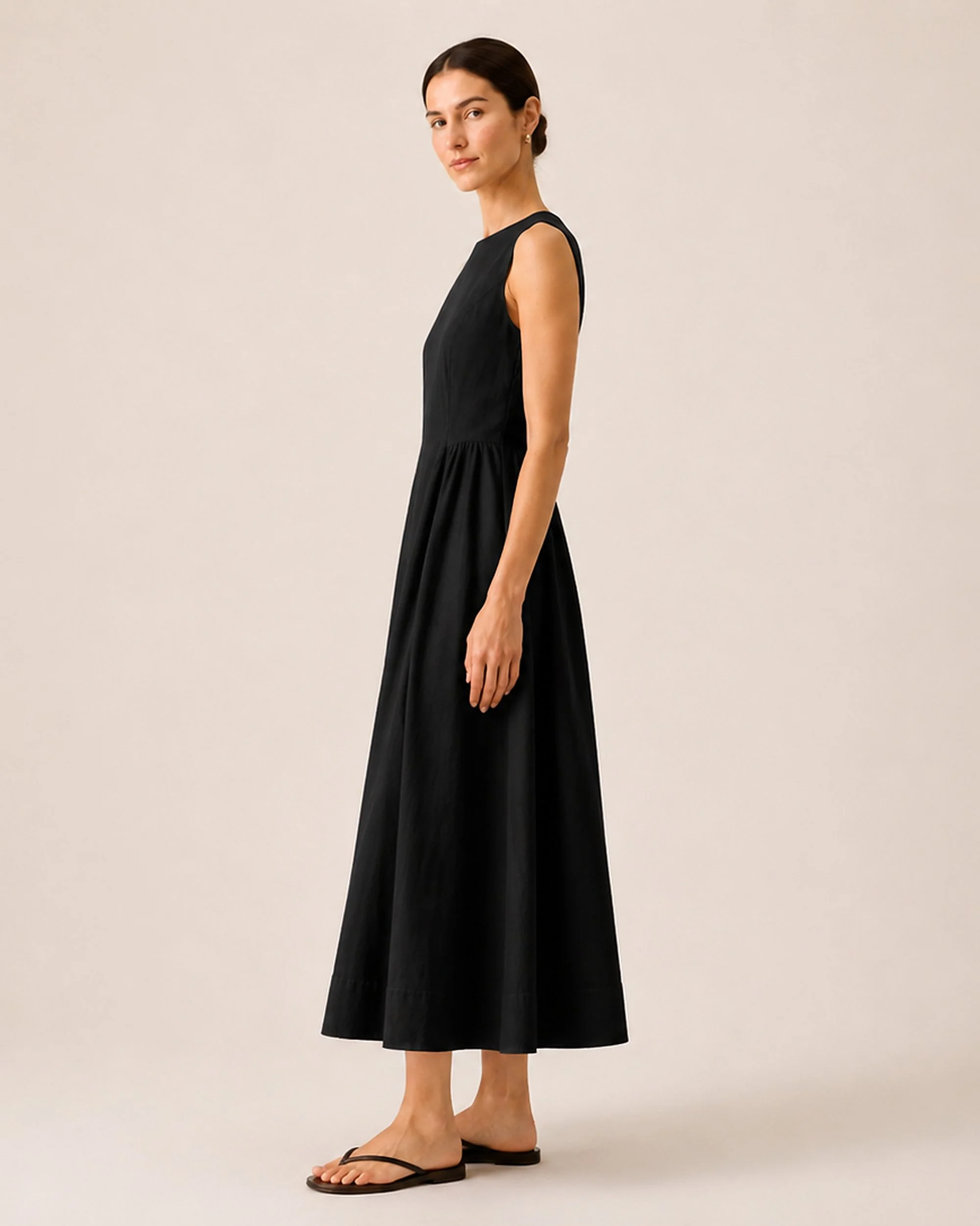 Side view of The Flax Studio black Tailored Dress, showing the fitted bodice and flared skirt.
