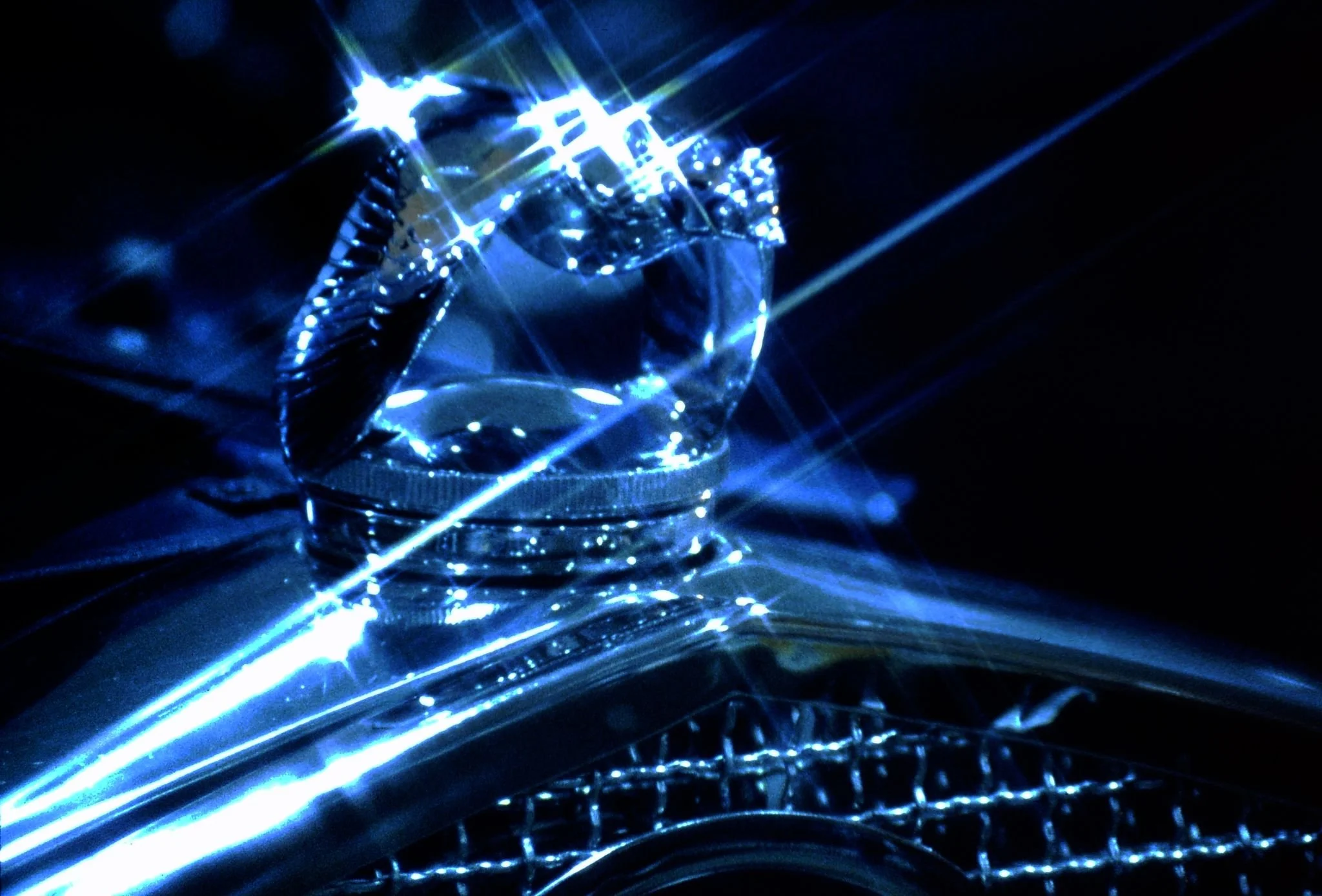 Close-up of a glass cube illuminated with blue and white lights, creating starburst effects on a dark background.