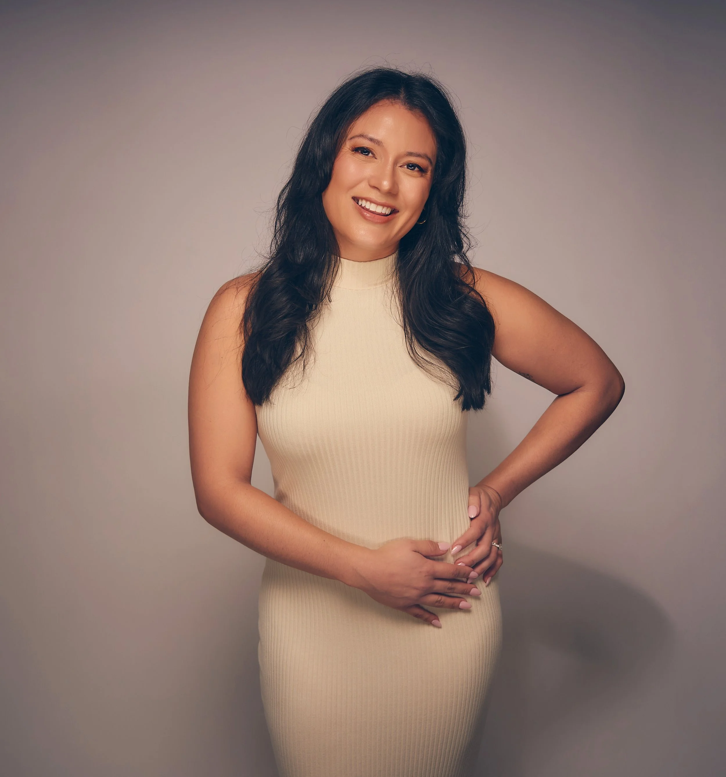 Jane Messersmith: A woman with long dark hair, smiling, wearing a sleeveless beige top, standing against a plain background.