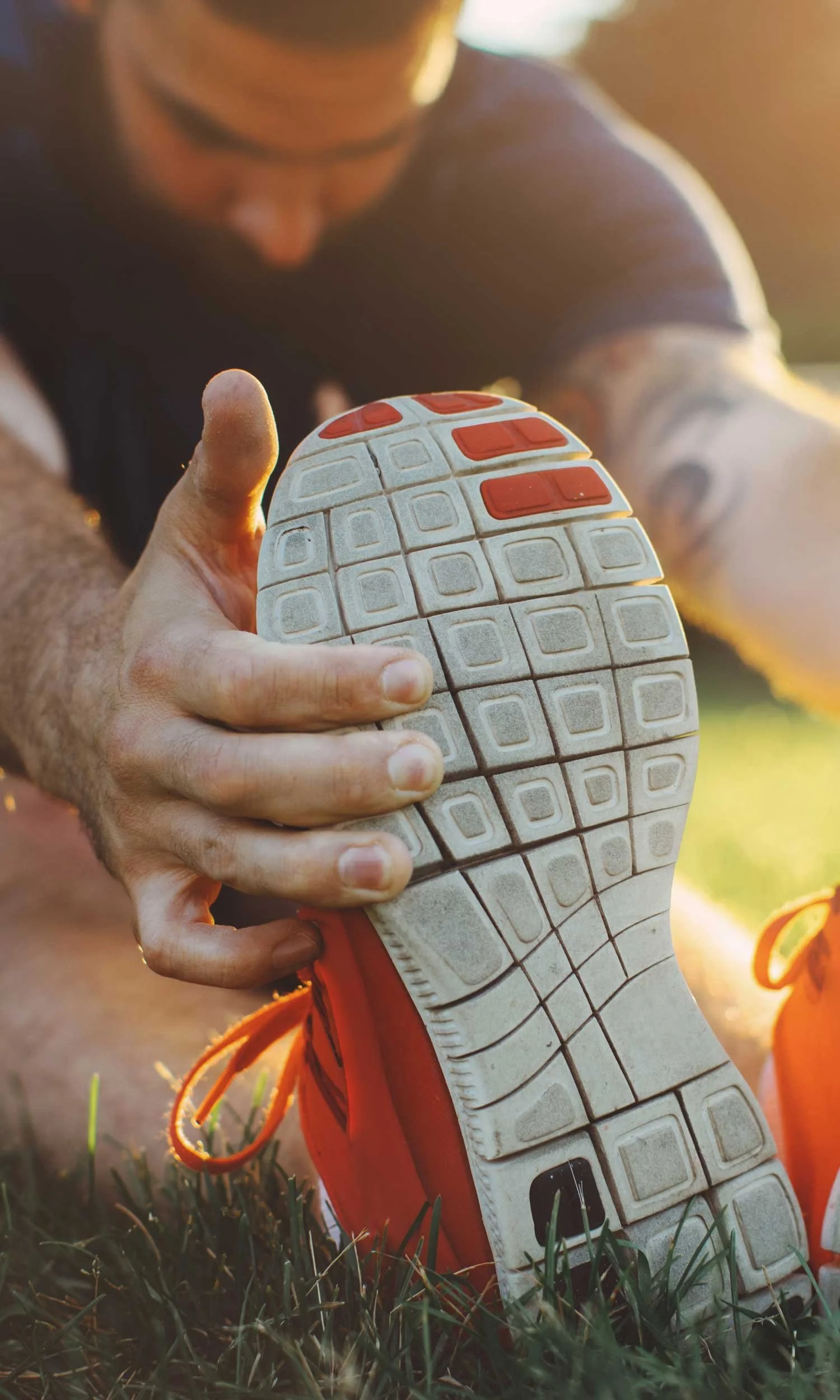 Man, sitting outside, stretching forward and holding toes