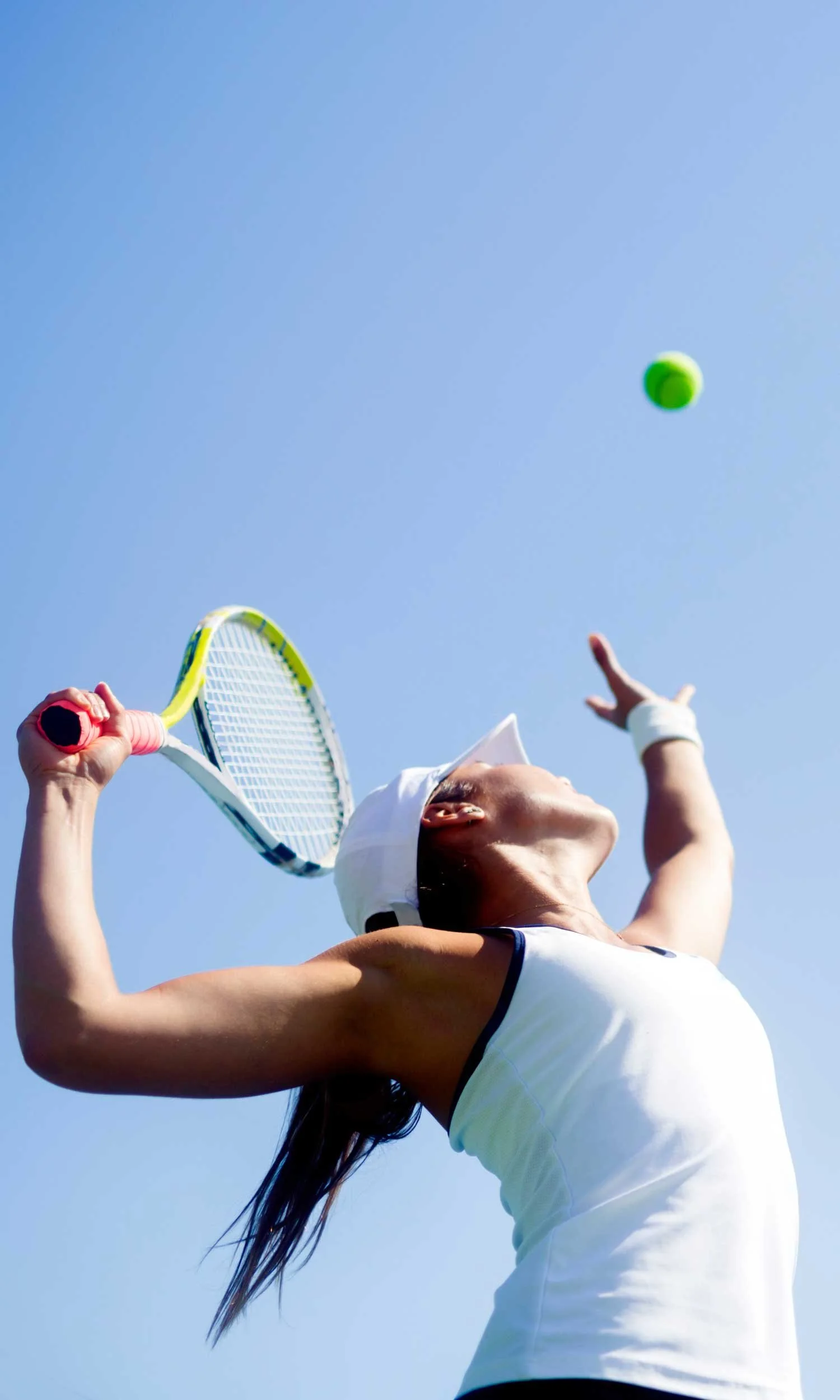 Woman holding tennis racket serving tennis ball