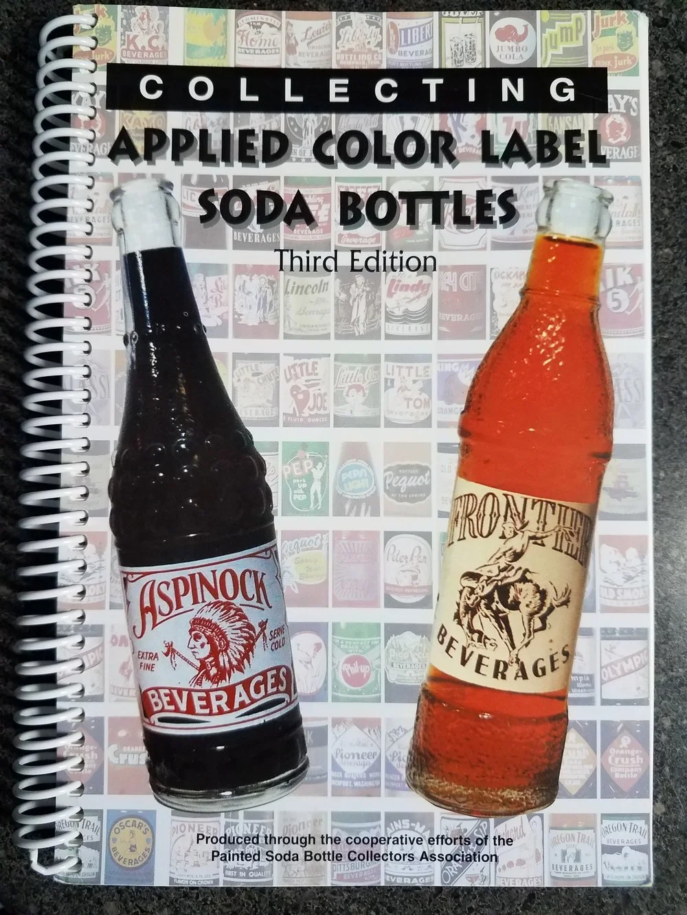 Cover of a book titled "Collecting Applied Color Label Soda Bottles, Third Edition" featuring two soda bottles, one Aspinock and one from Troy, with a background of smaller vintage soda label images.