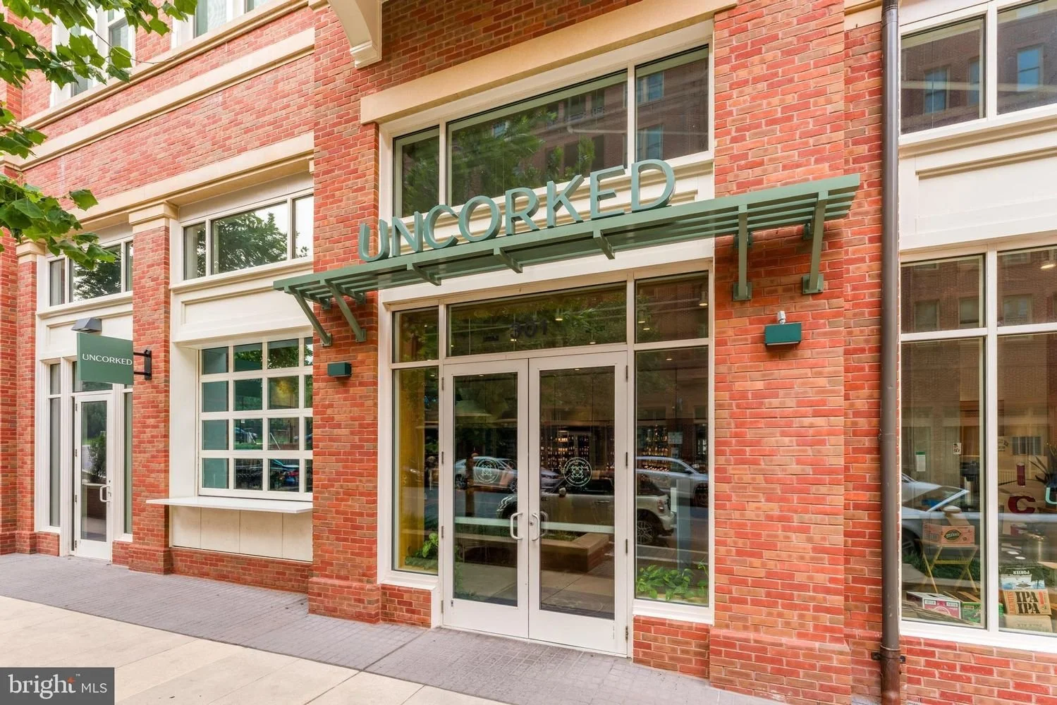 The exterior of a brick building with a sign that reads "UNCORCKED" above the entrance, which has glass double doors, and a smaller sign on the side.