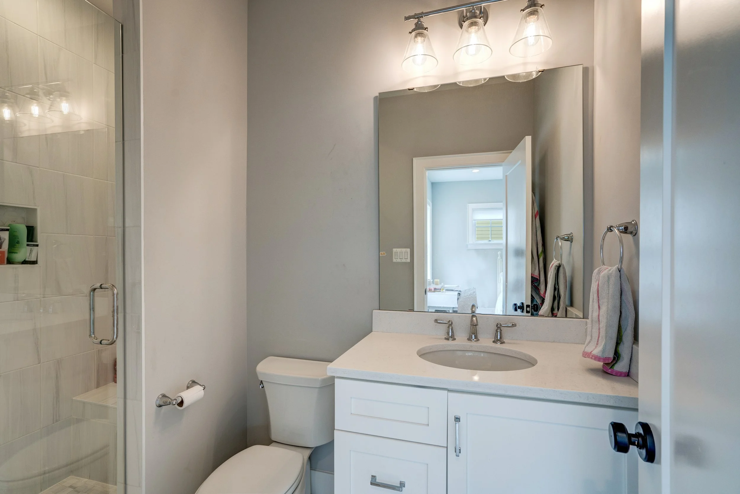 Bathroom with a vanity, mirror, towel rack, and shower stall with glass door.