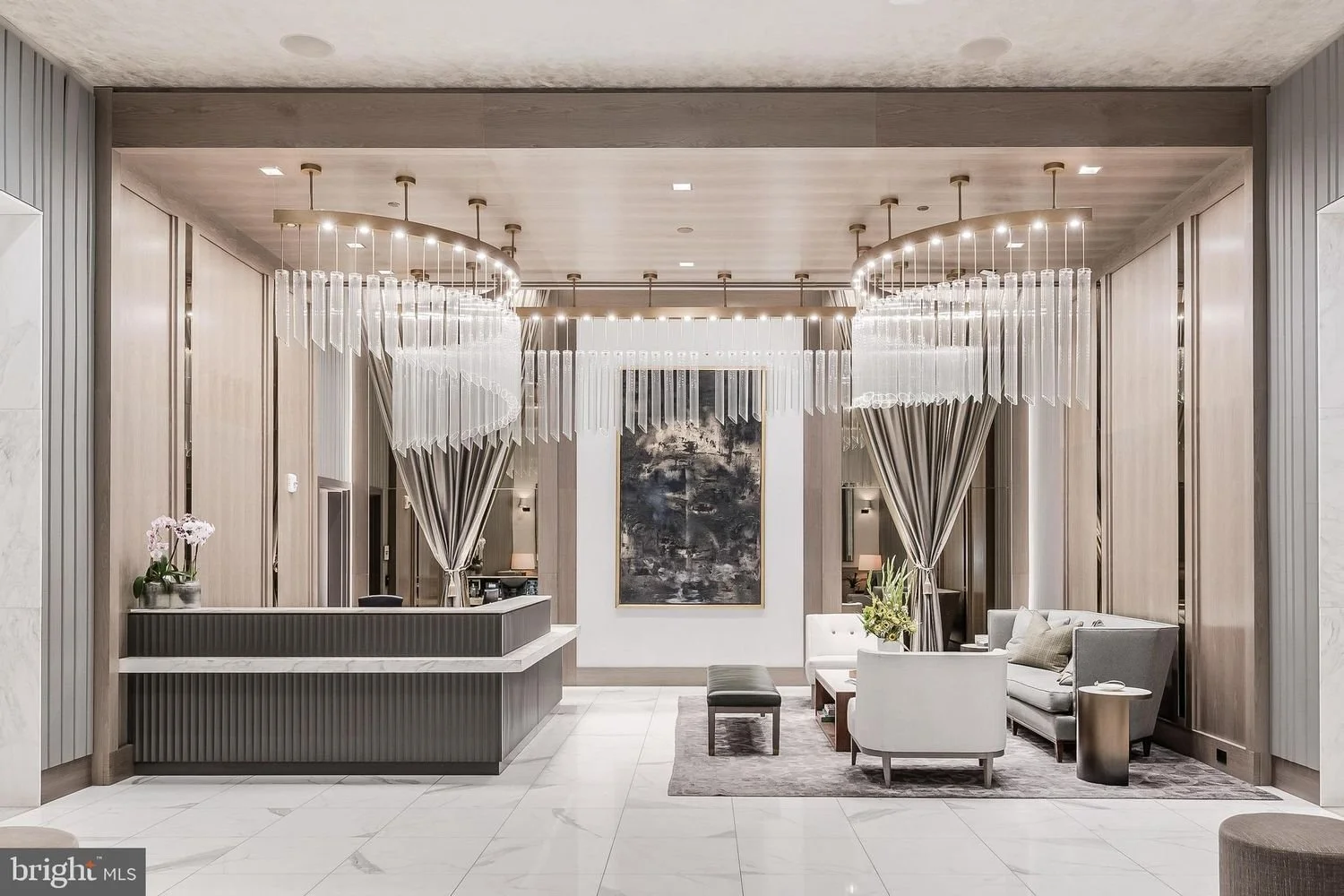 Hotel lobby with modern decor, abstract artwork, and a seating area with chairs, sofa, and a coffee table.