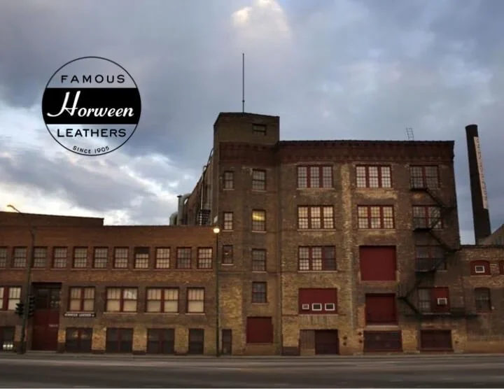 Old brick building with multiple windows and fire escape, under a cloudy sky, advertising for Horween Leather company.