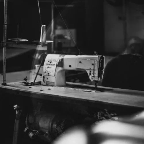 Black and white photo of an industrial sewing machine on a work table.