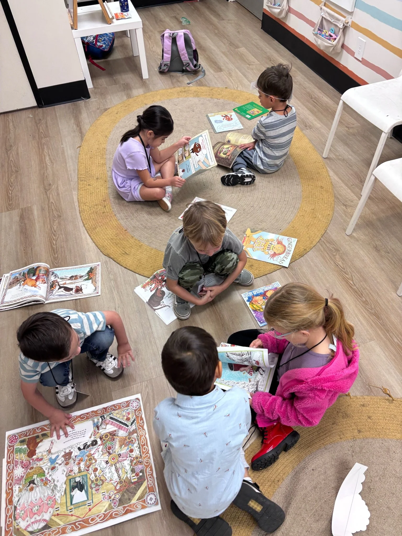 Children sitting on the floor reading colorful storybooks.