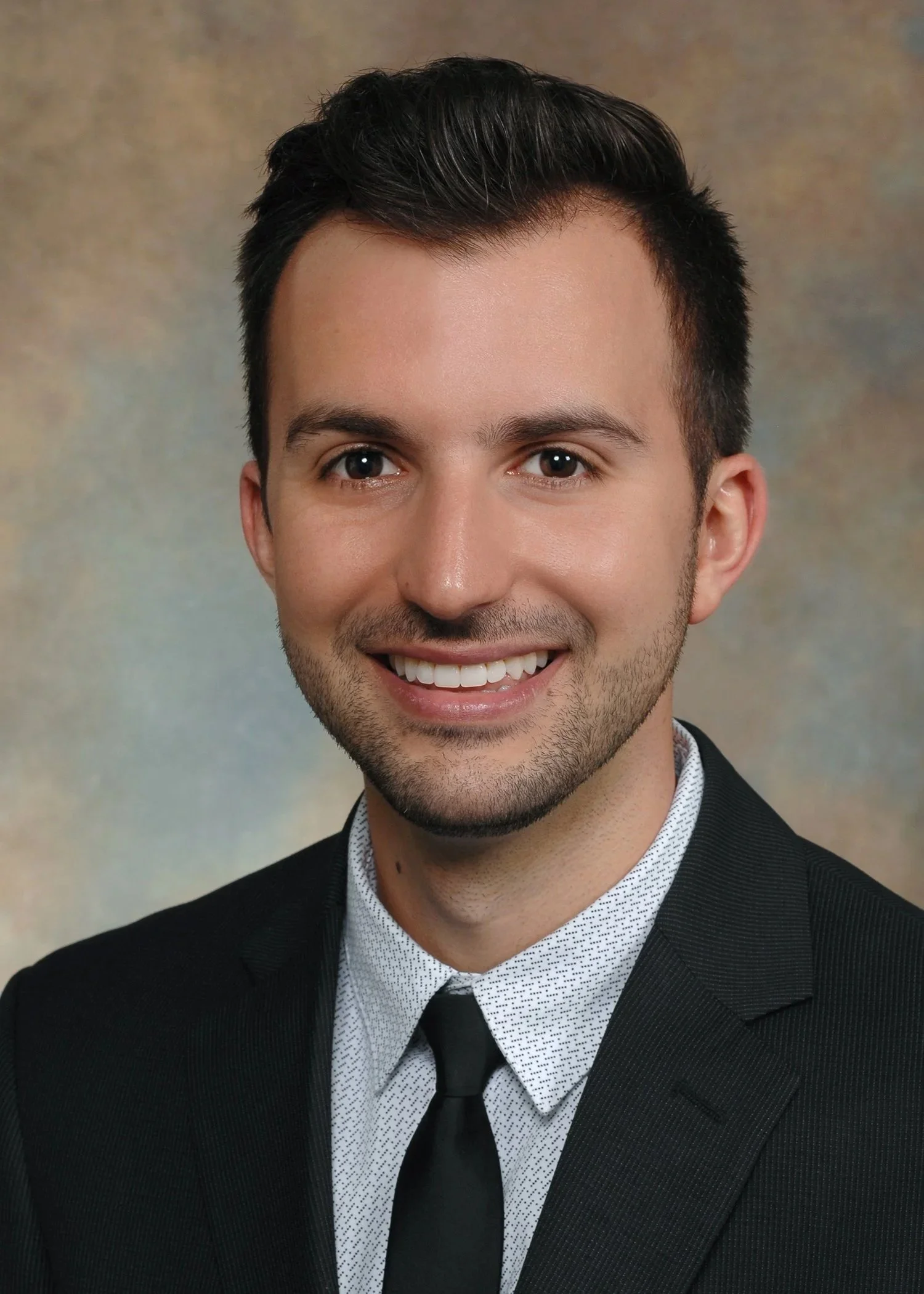 Michael, a CRNA and founder of Talmiro, smiling in a black suit.
