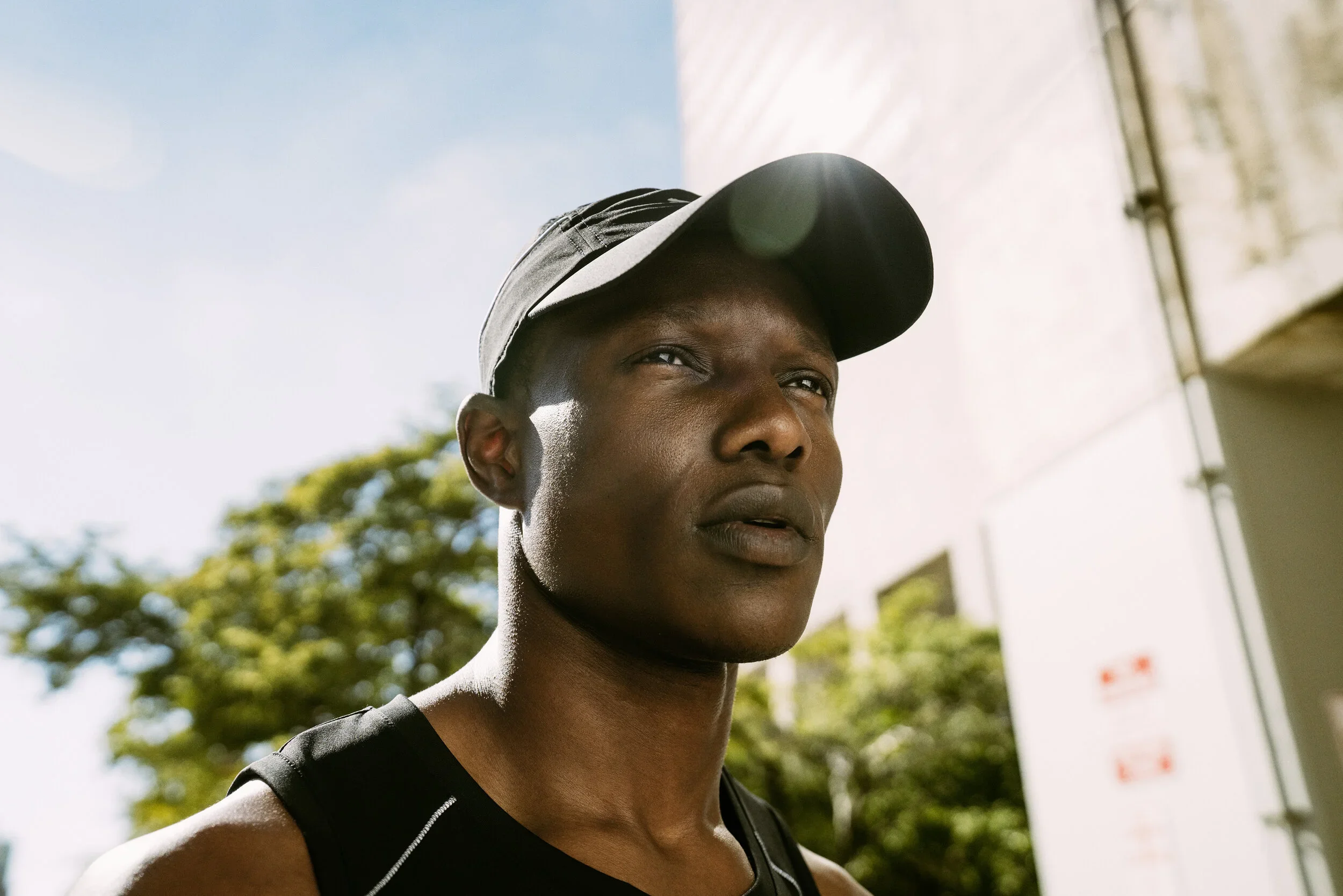 Close-up of an African American woman wearing a baseball cap outdoors on a sunny day.