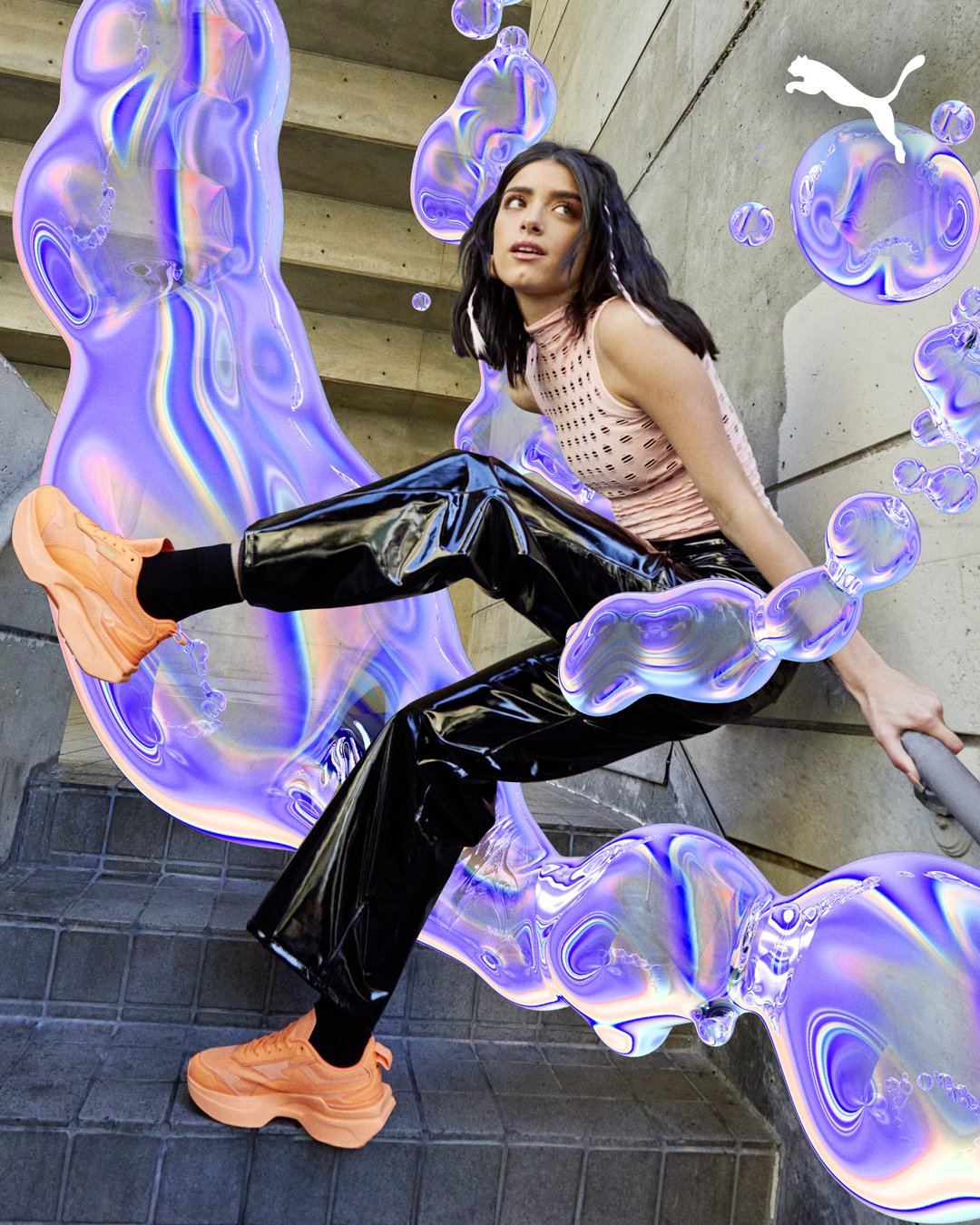 A woman in athletic attire, wearing peach sneakers, black shiny pants, and a pink sleeveless top, is posed on a staircase with colorful, holographic digital effects surrounding her in an urban setting.