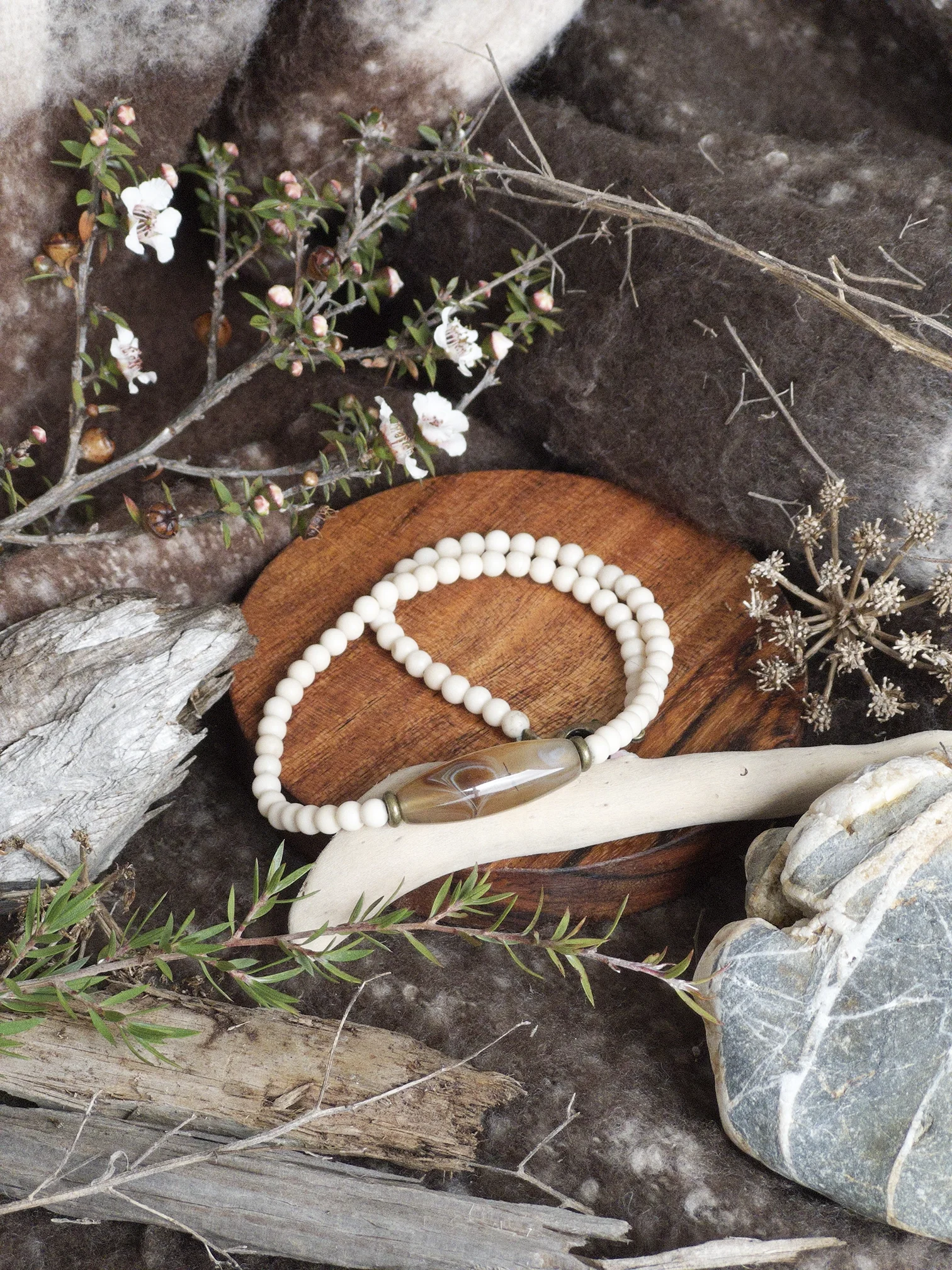 White Necklace on Brown Coaster.webp