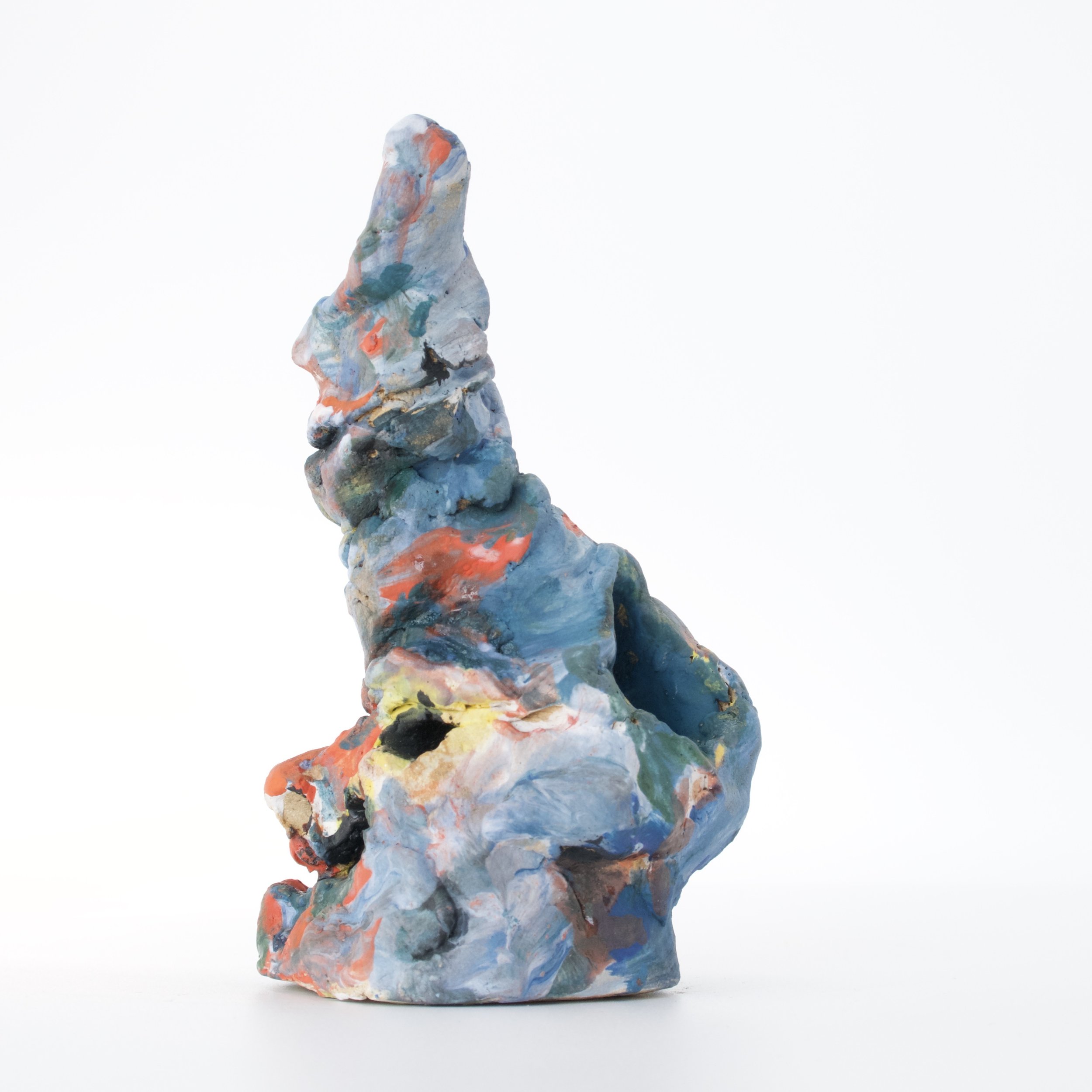 Colorful abstract sculpture resembling a twisted, elongated shape painted with various shades of blue, orange, gray, green, and black, set against a plain white background.