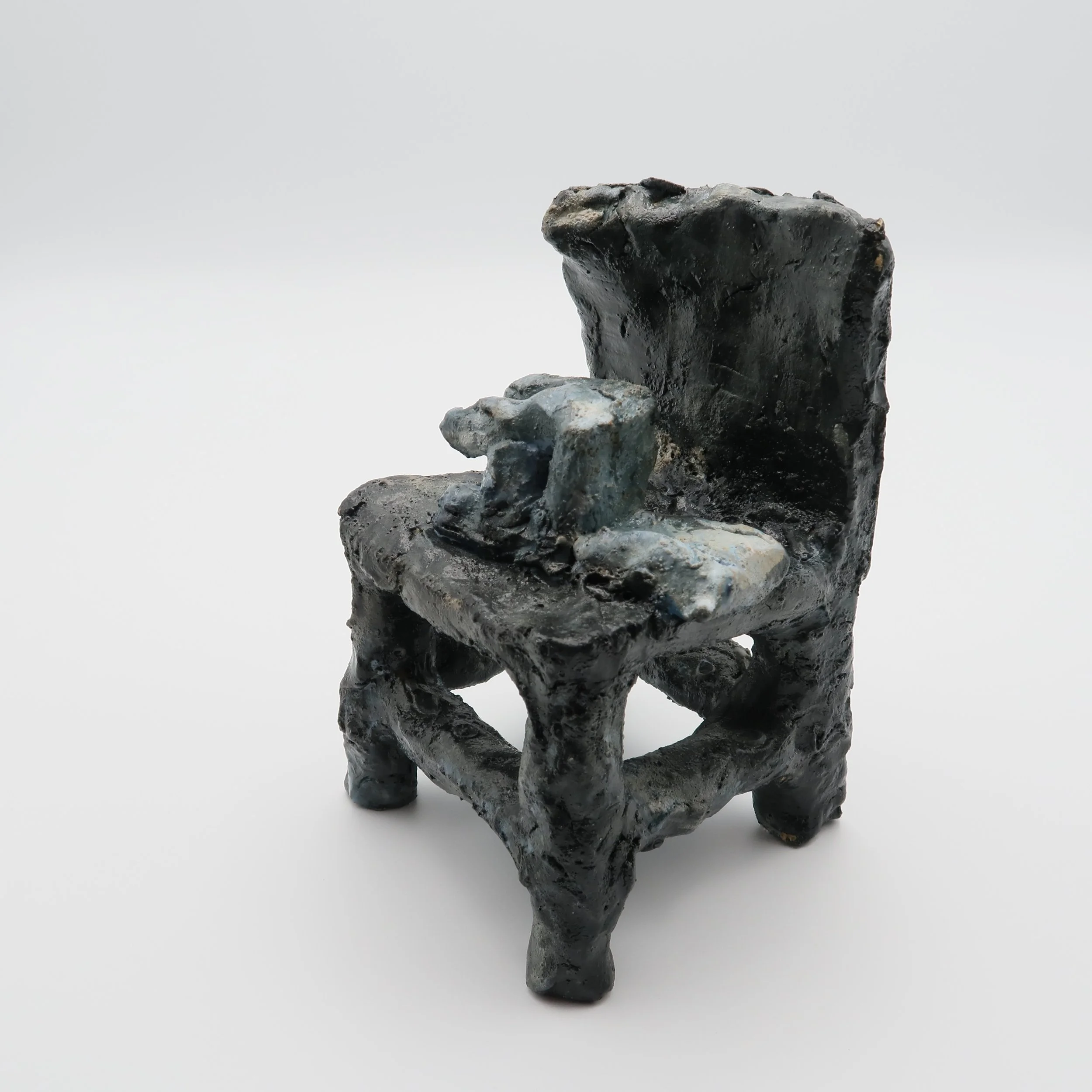 A small black sculpture of a dog, sitting on a white surface against a plain white background.