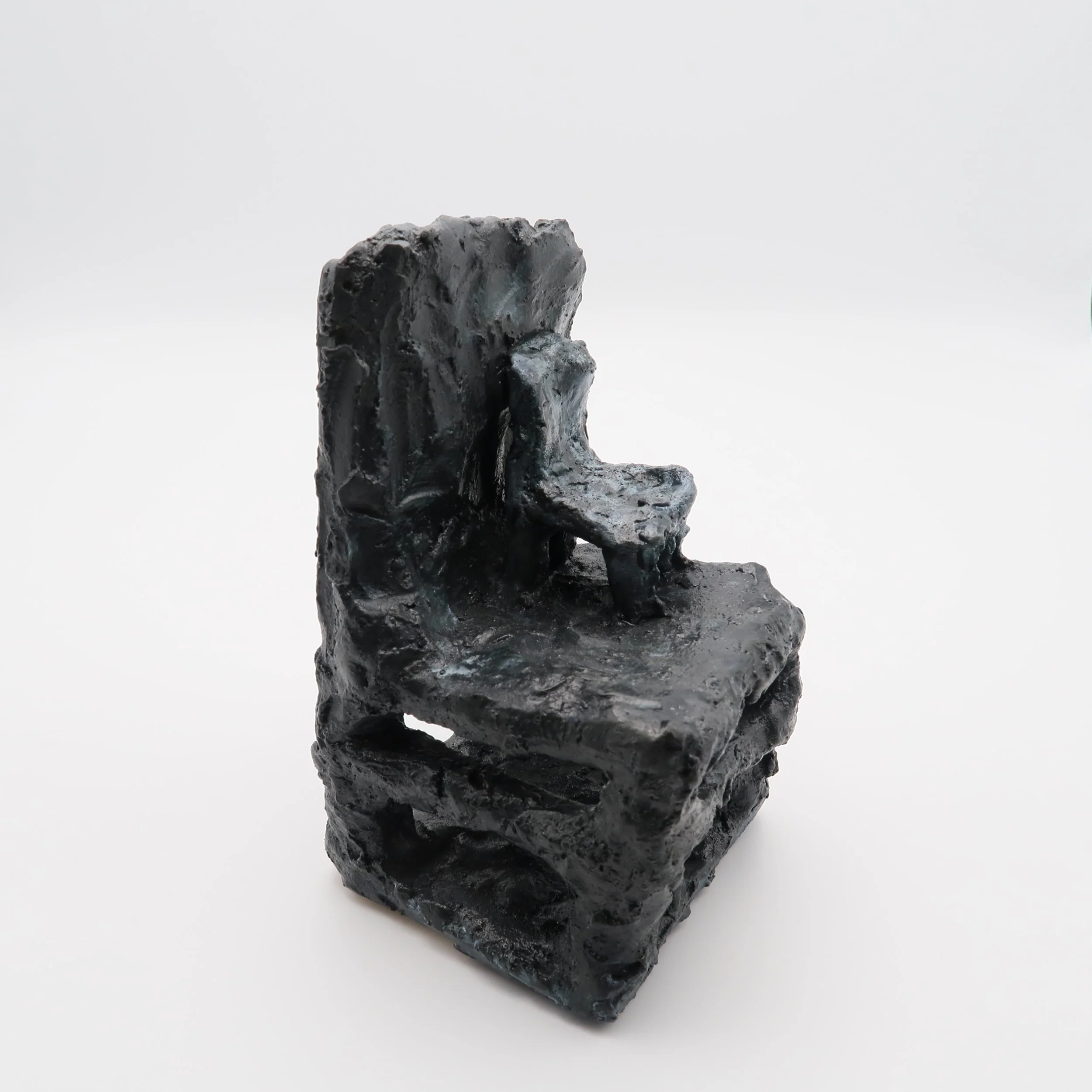 A dark, rough, irregularly shaped volcanic rock on a white background.