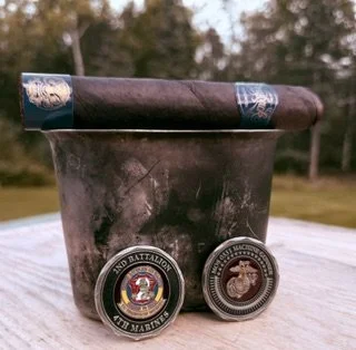 Room101 Big Payback 70s Maduro resting on a military-style metal cup with U.S. Marine Corps challenge coins.