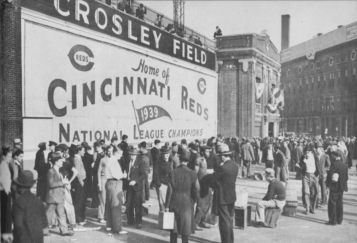 A black and white photo of a crowd of people outside Crosley Field, with a large sign celebrating the Cincinnati Reds as 1939 National League Champions.