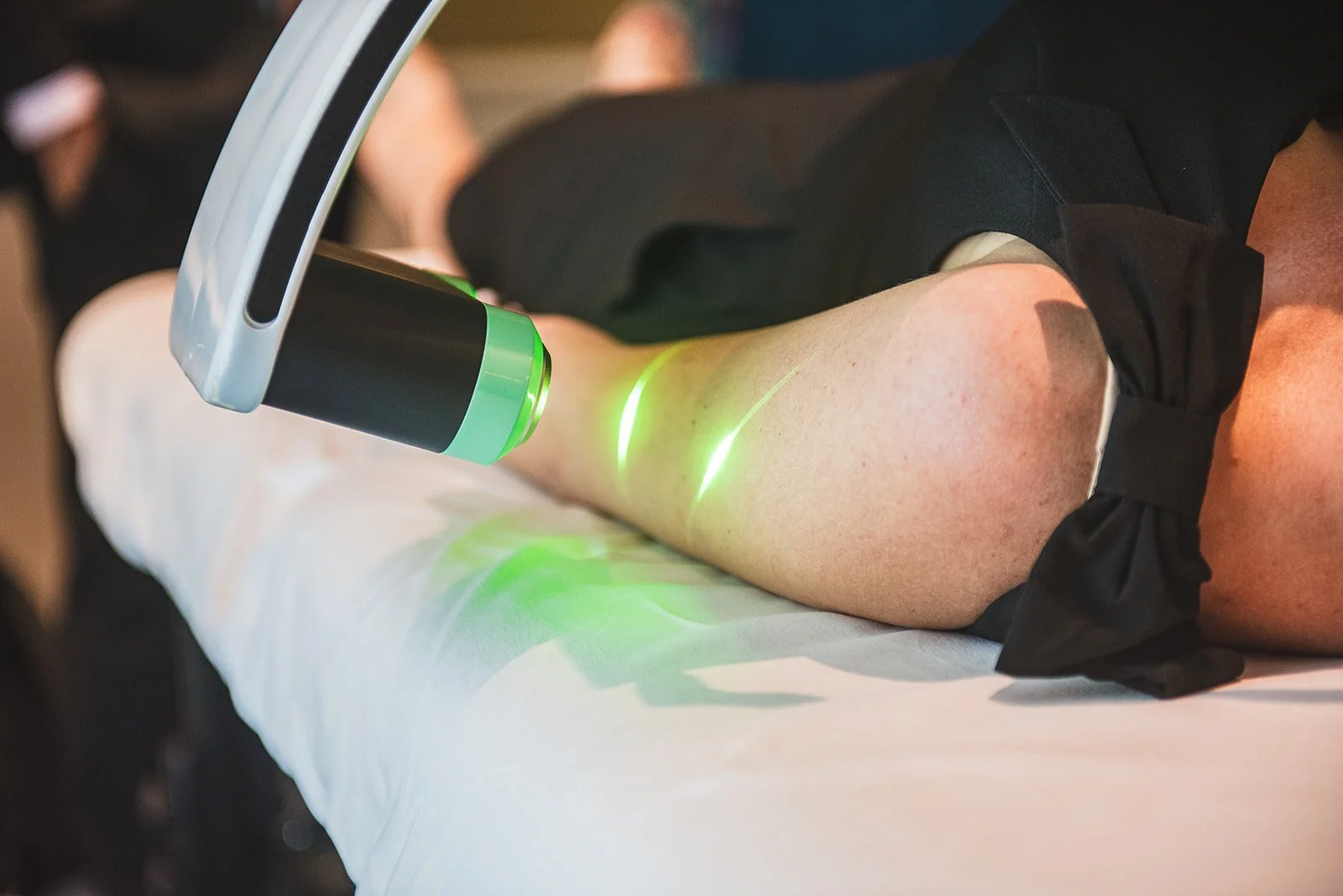 Person receiving laser therapy on their leg in a clinical setting.