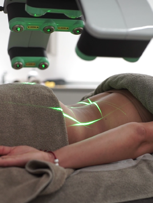 Client receiving Erchonia Emerald Laser therapy, with green low-level laser light directed across the neck and upper chest.