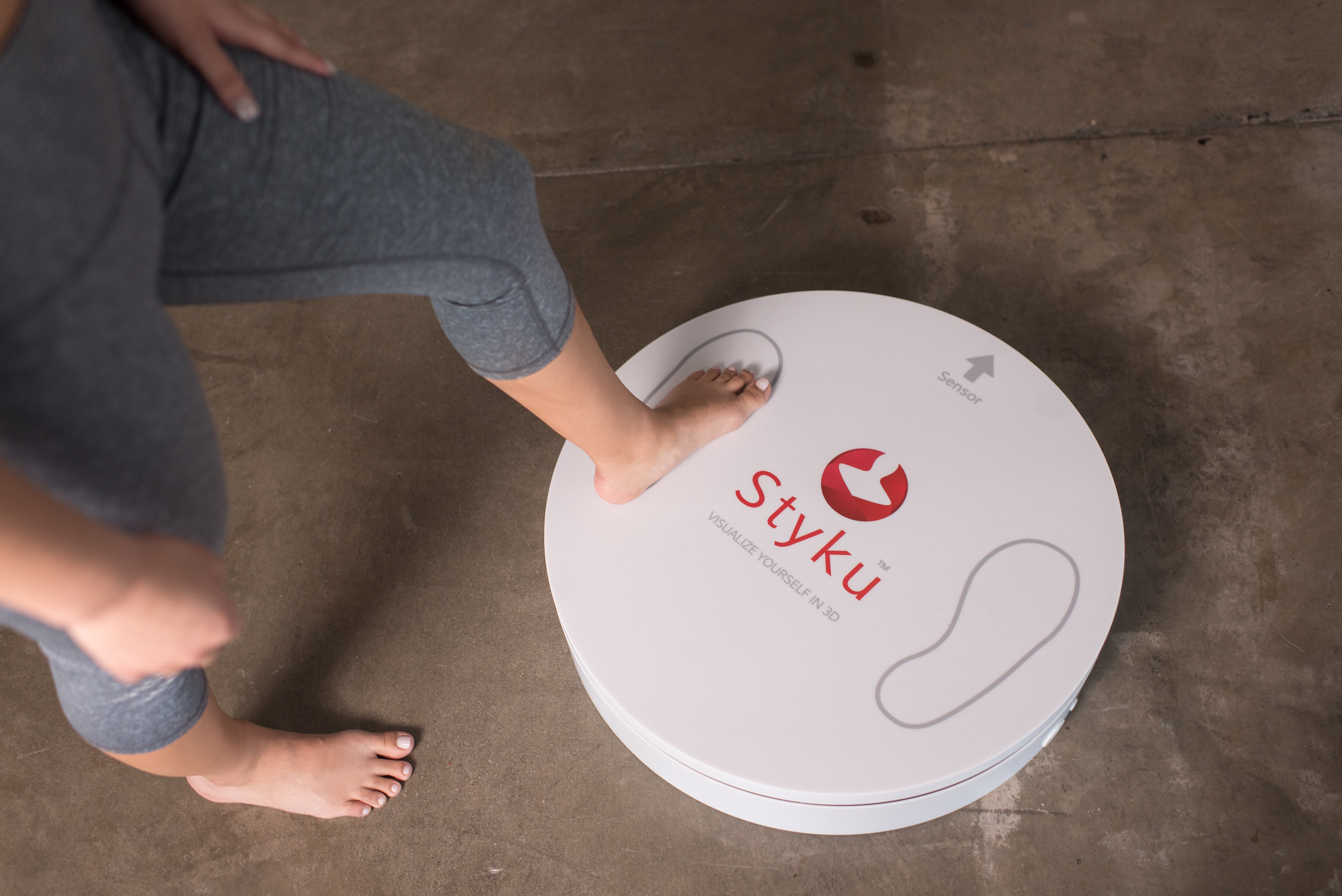 Person stepping onto a Styku 3D body scanner for body measurement scanning
