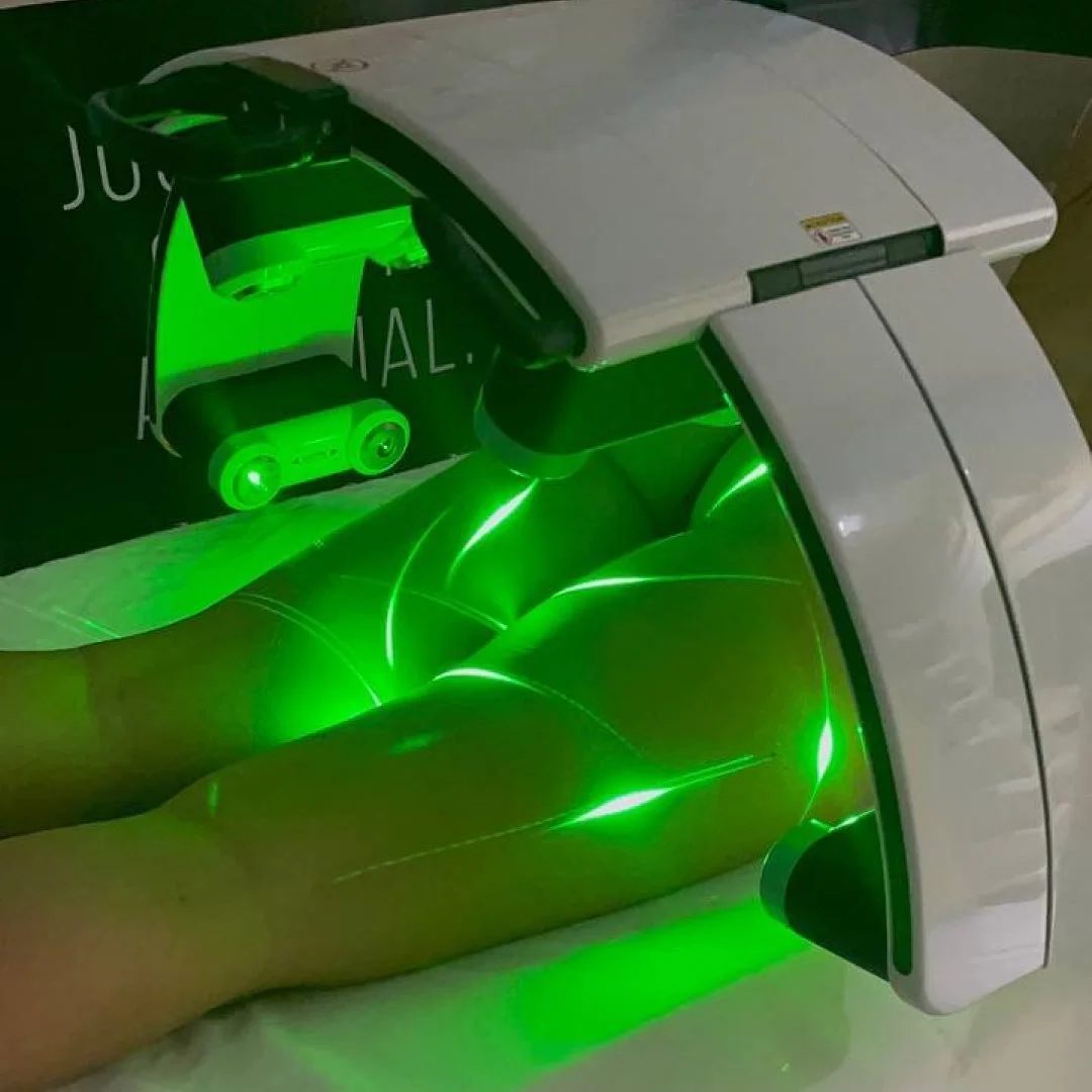 Client receiving Erchonia Emerald Laser therapy, with the lower body positioned beneath the treatment device during a session.