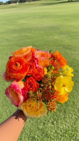 Person holding a colorful bouquet of roses and other flowers on a golf course
