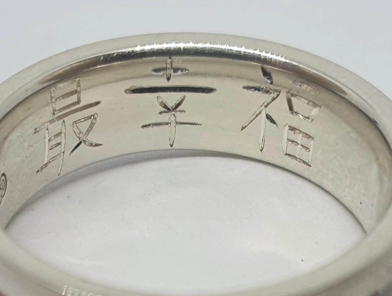 Close-up of a white gold wedding band ring hand engraved internally with Chinese characters.