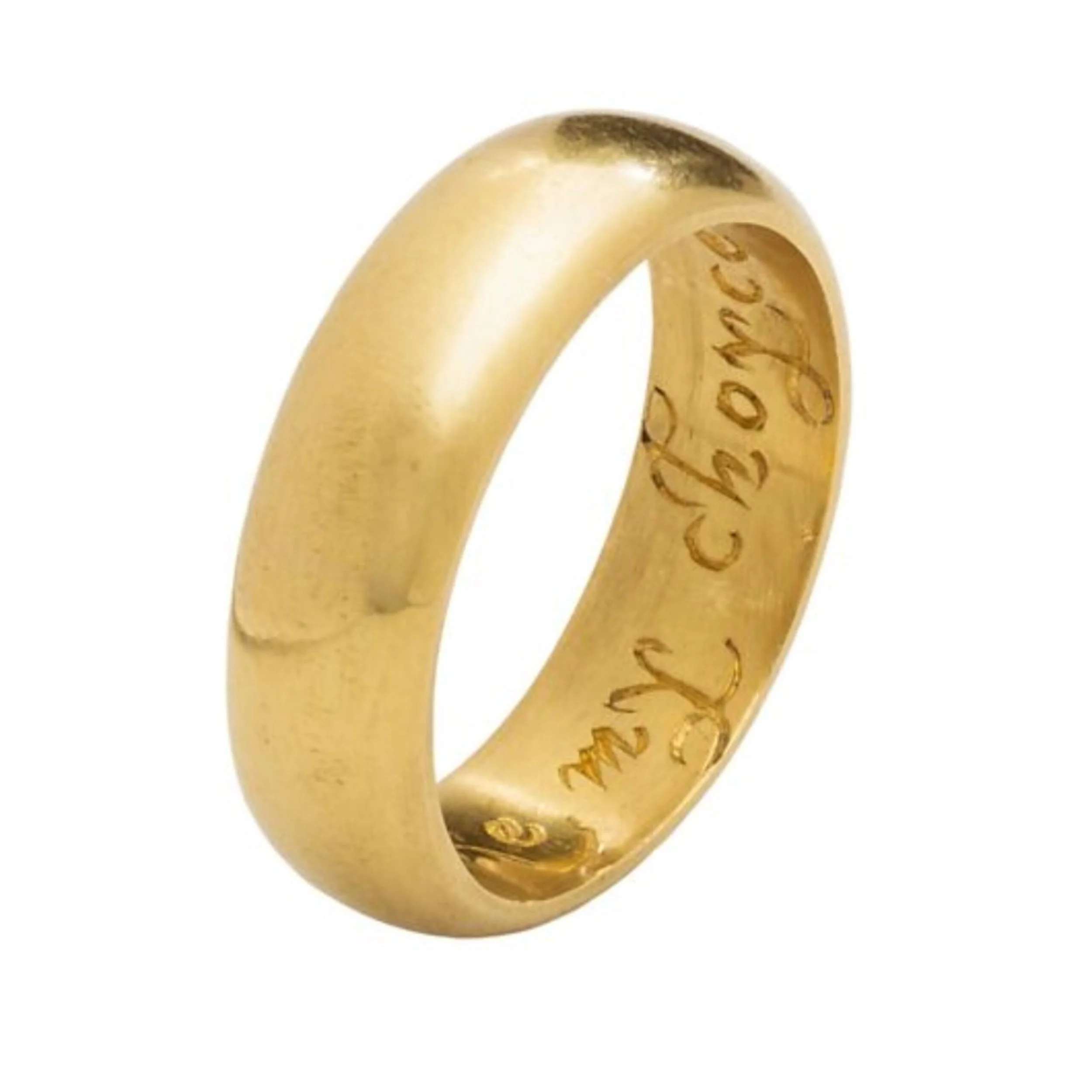 Close-up of a gold wedding ring with engraved text inside.