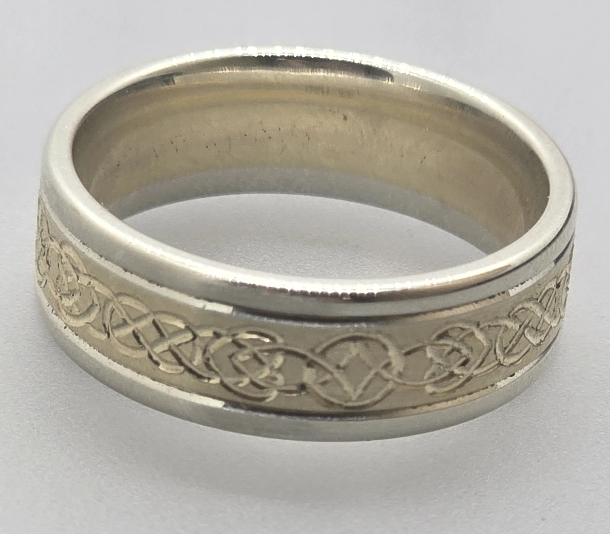 Close-up of a yellow gol and white gold wedding or engagement band featuring a unique bespoke celtic knotwork hand engraved pattern.