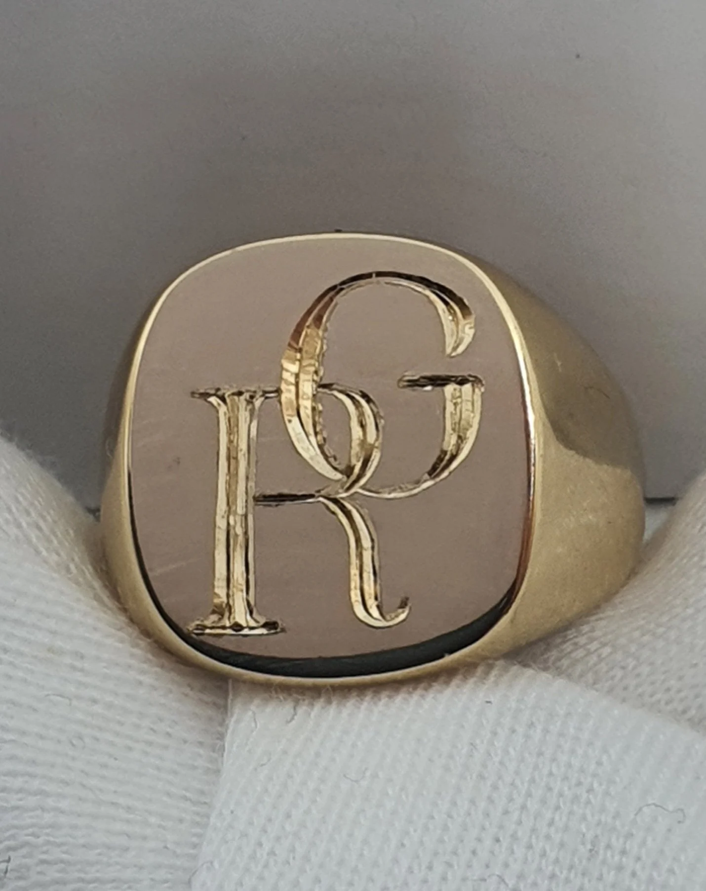 Close-up of an expertly hand engraved gold signet ring with a personalised bespoke custom monogram design.