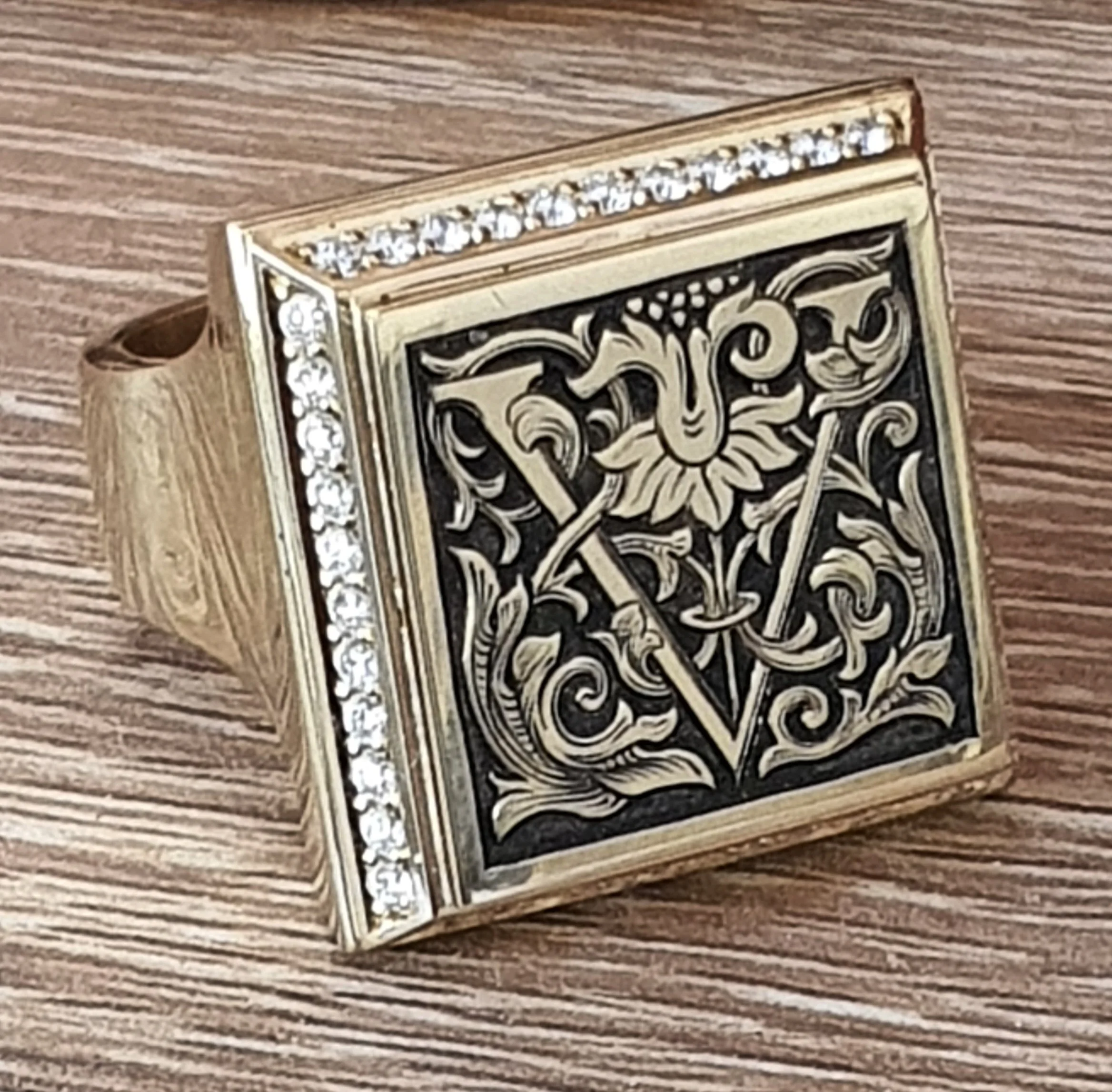 Close-up of a decorative ring with intricate black and gold hand engraving. bespoke jewellery