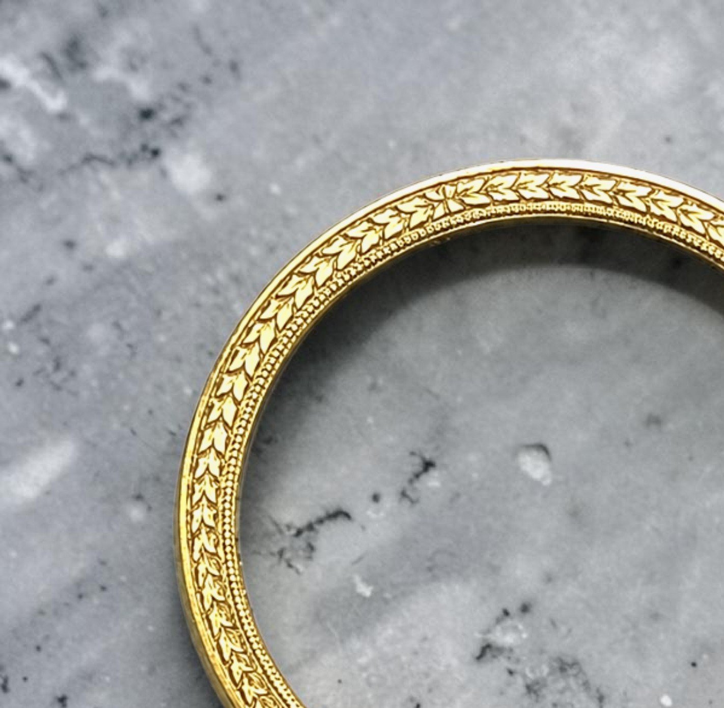 Close-up of a yellow gold wedding or engagement band featuring a unique, delicate, vintage, bespoke botanical hand engraved pattern.