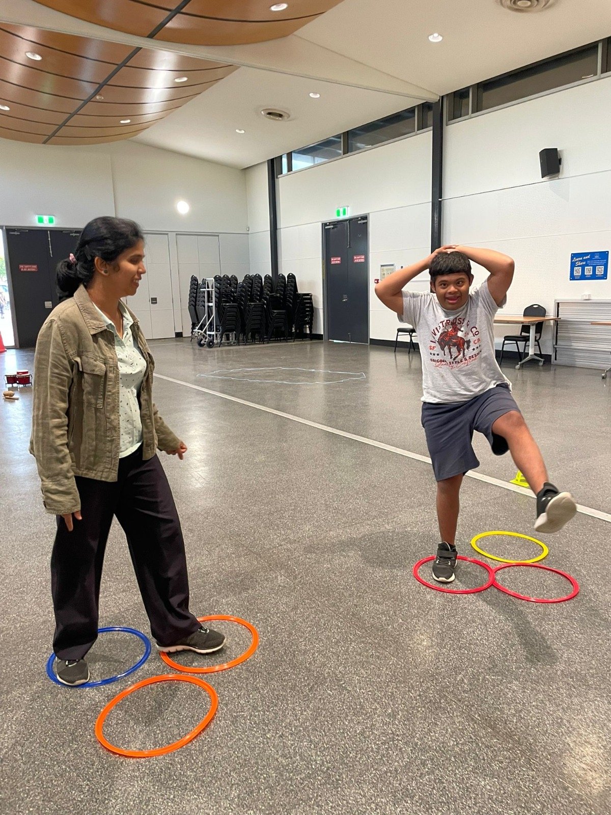 A disabled boy dancing between medium hoops on the ground as part of a Capoeira class