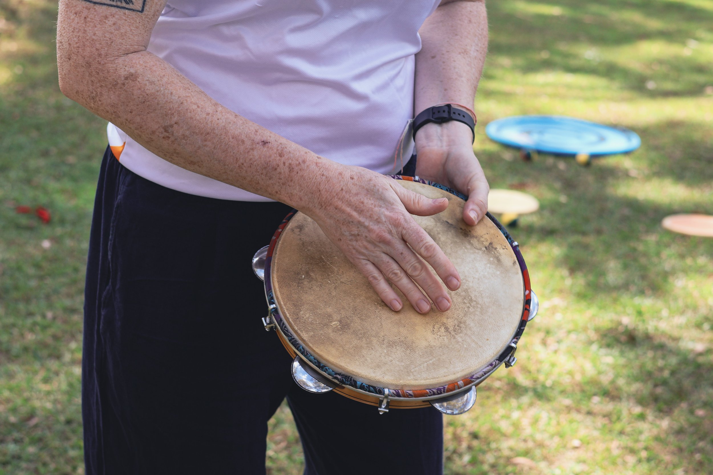An adult playing a tamborine on a lawn